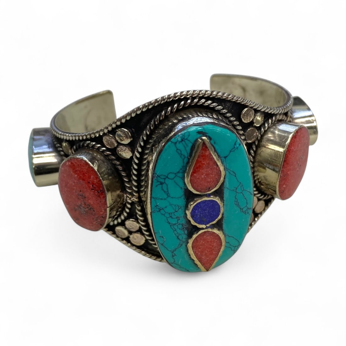Vintage Himalayan Tribal Turquoise Coral Lapis Silver Cuff Bracelet, mid-20th Century, 170g: This substantial vintage Himalayan cuff bracelet, likely crafted in Nepal or Tibet during the mid-20th century, is a powerful statement of traditional jewelry artistry. At its center, an elongated tur