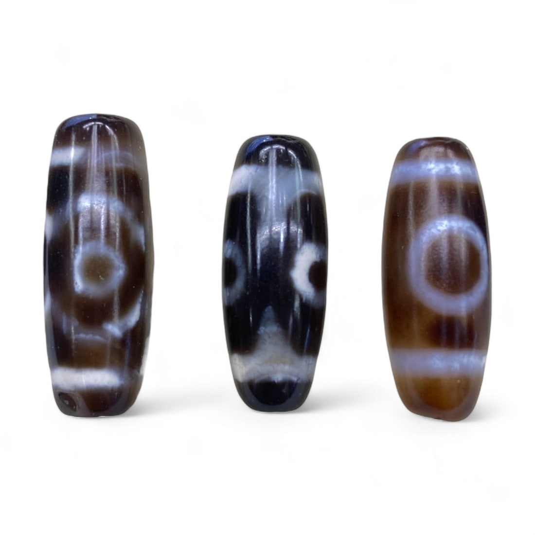 Lot of Tibetan Chung Dzi Beads, 3cm: This lot of Tibetan Dzi beads features the traditional etched agate designs prized for their protective and spiritual qualities. Each bead is cylindrical, displays crisp white patterns against a deep 