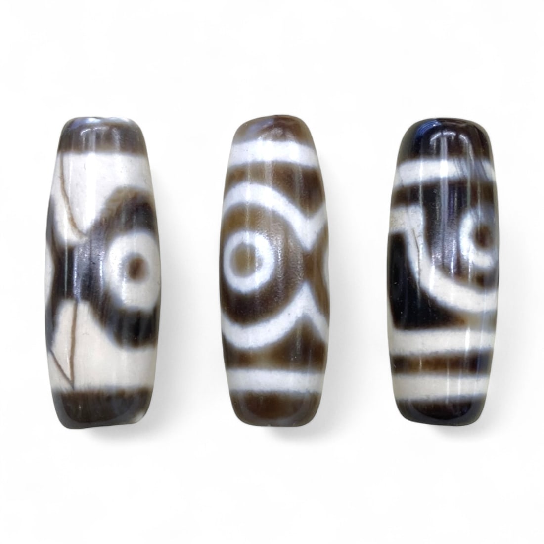 Lot of Tibetan Chung Dzi Beads, 3cm: This lot of Tibetan Dzi beads features the traditional etched agate designs prized for their protective and spiritual qualities. Each bead is cylindrical, displays crisp white patterns against a deep 