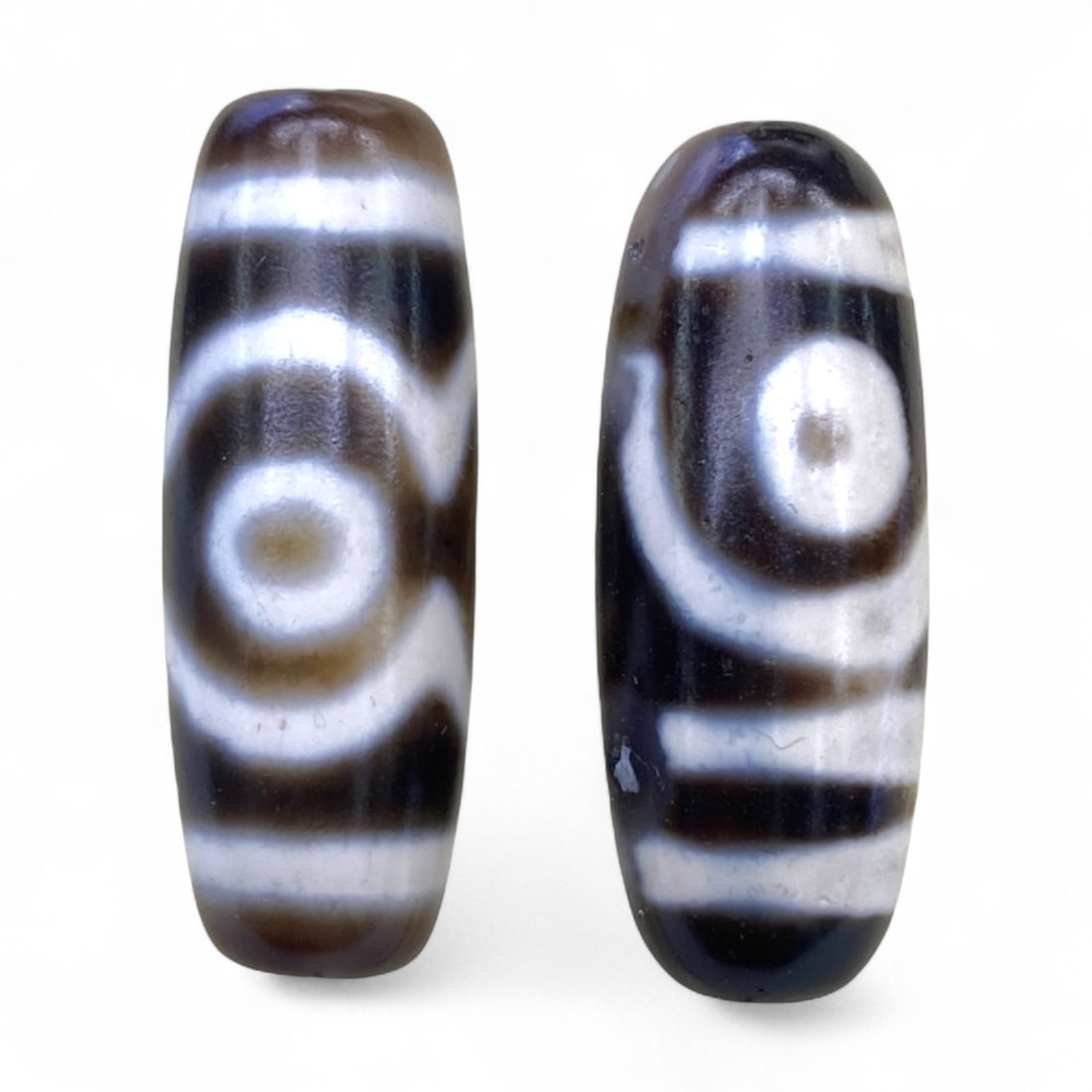 Lot of Tibetan Chung Dzi Beads, 3cm: This lot of Tibetan Dzi beads features the traditional etched agate designs prized for their protective and spiritual qualities. Each bead is cylindrical, displays crisp white patterns against a deep 