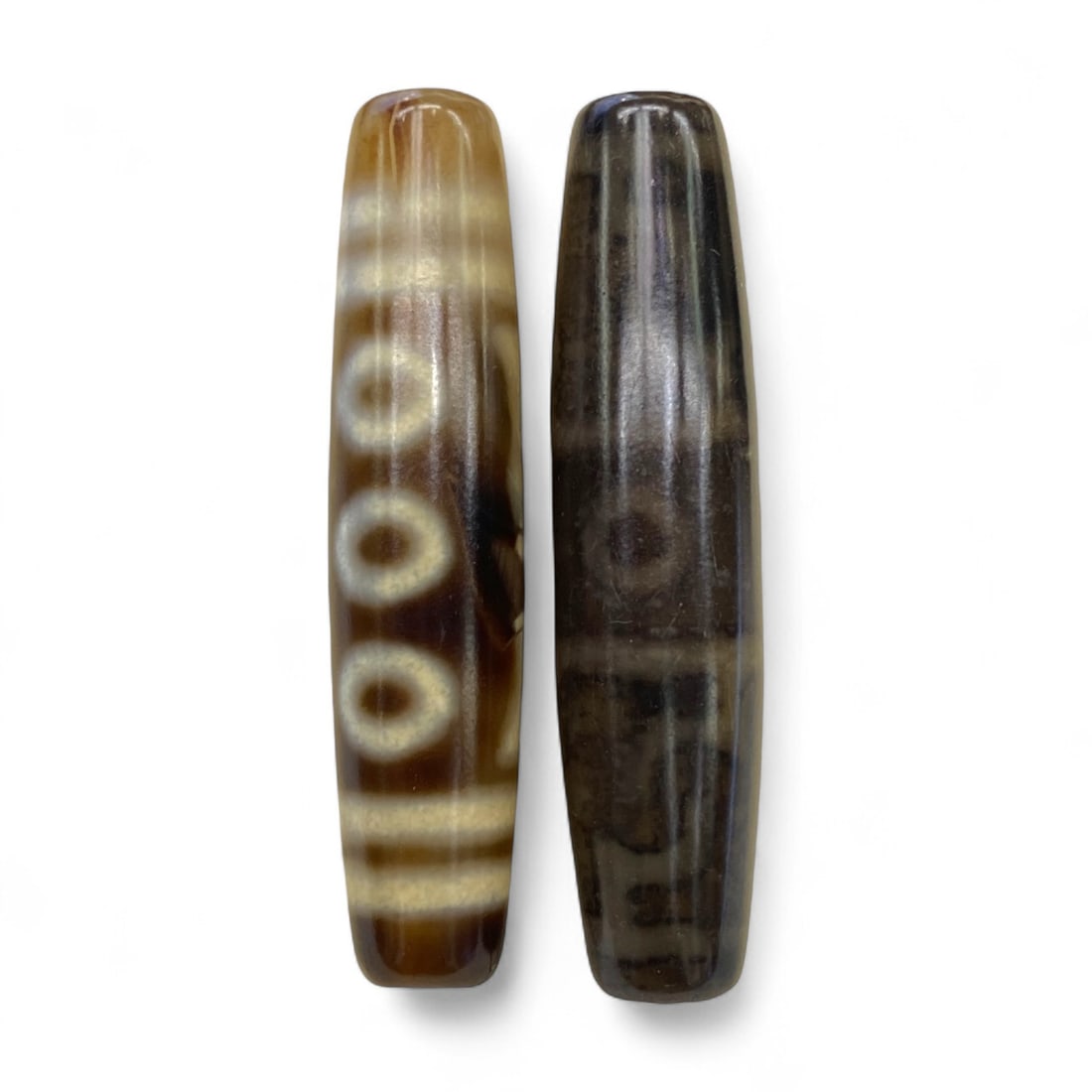 Lot of Tibetan Chung Dzi Beads, 6cm: This lot of Tibetan Dzi beads features the traditional etched agate designs prized for their protective and spiritual qualities. Each bead is cylindrical, displays crisp white patterns against a deep 
