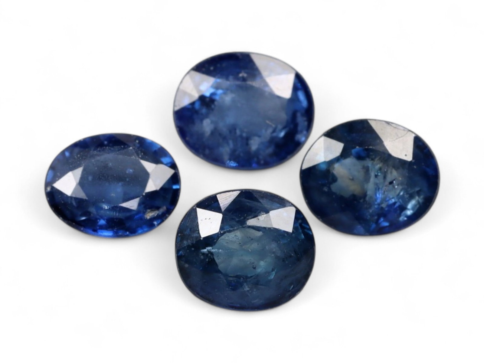 3.22 Carats Deep Blue Sapphire Oval Lot - Natural Beryllium-Treated Stones: This lot of oval-cut sapphires exhibits a deep, inky blue hue with flashes of royal and midnight tones under shifting light. Each stone is faceted to bring out its natural luster, with internal inclus
