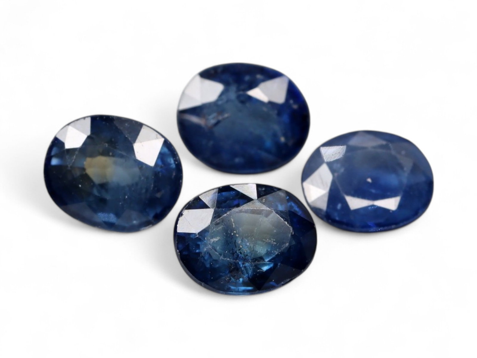 3.31 Carats Deep Blue Sapphire Oval Lot - Natural Beryllium-Treated Stones: This lot of oval-cut sapphires exhibits a deep, inky blue hue with flashes of royal and midnight tones under shifting light. Each stone is faceted to bring out its natural luster, with internal inclus