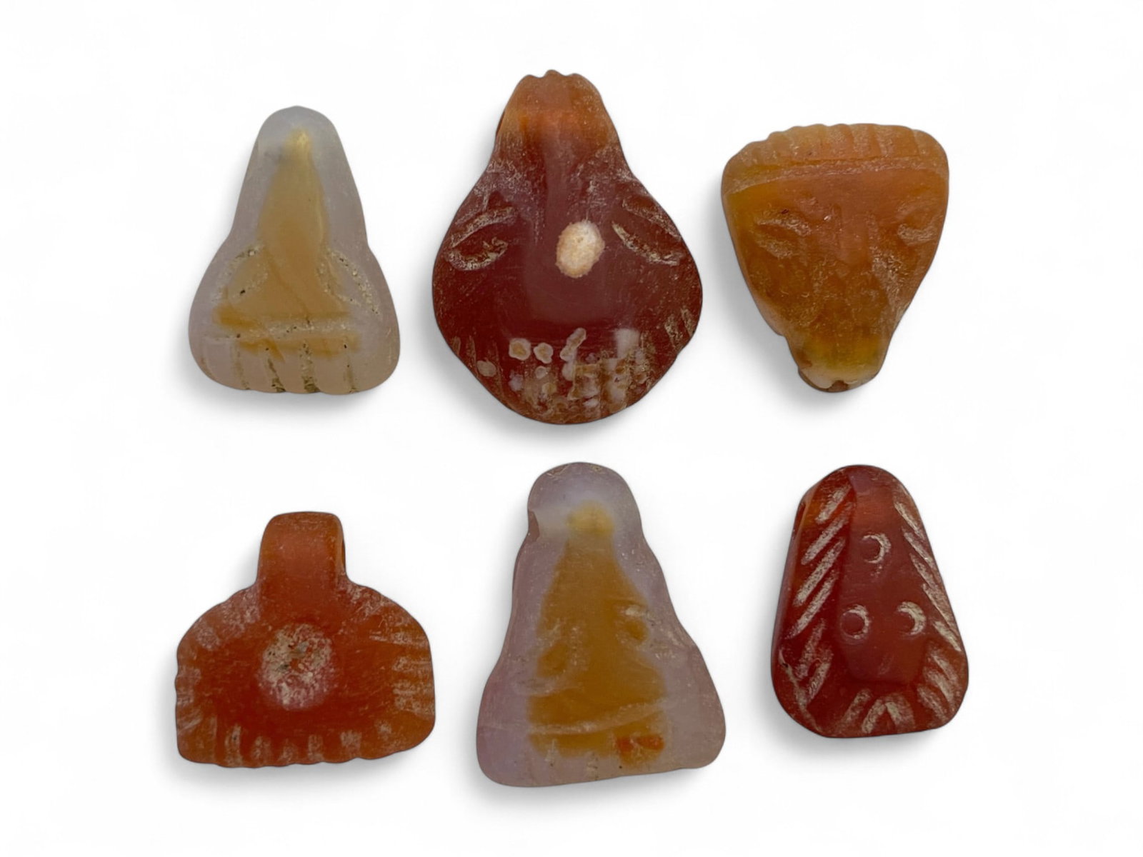 Ancient Coptic Egyptian Carnelian Face and Symbol Amulets, 6pcs, c. 4th-7th Century CE, 14g: This delicate collection of six miniature amulets, carved from translucent and banded carnelian, dates to the Coptic period of early Christian Egypt, approximately between the 4th and 7th century CE. 