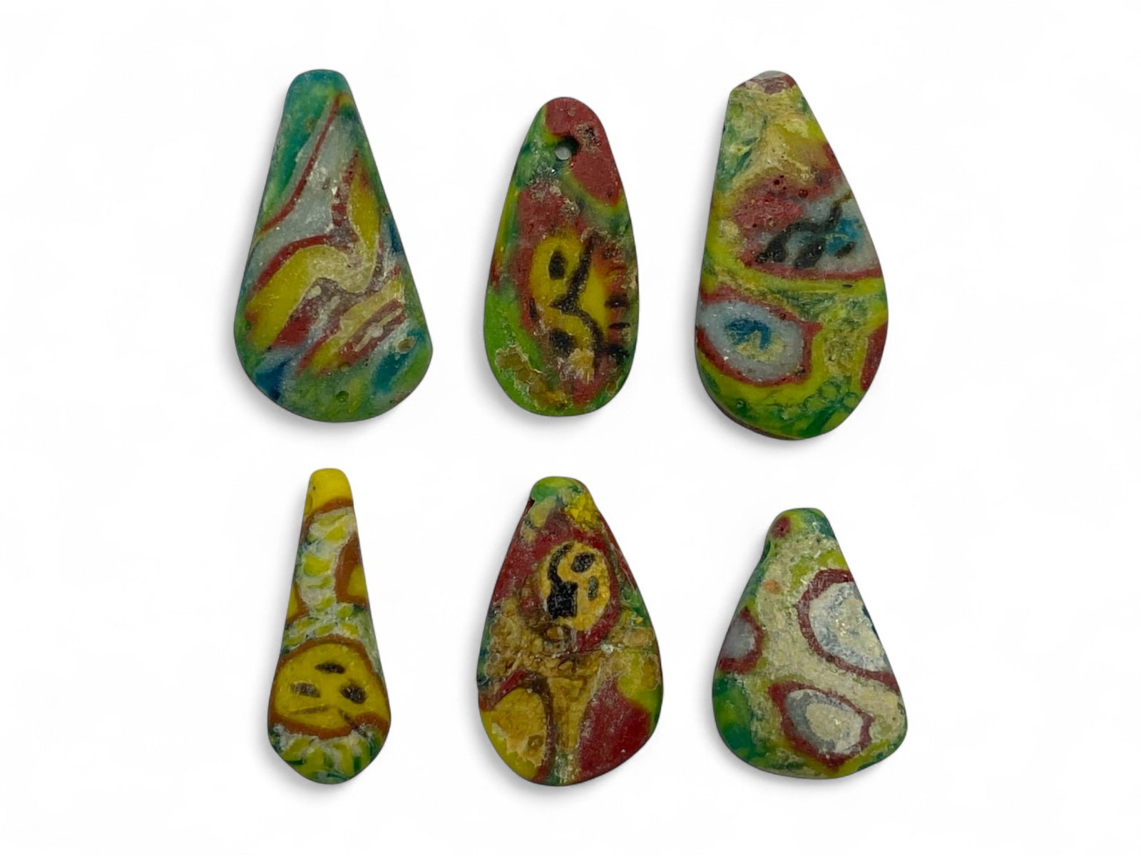 Ancient Egyptian Mosaic Glass Face Beads Set of 6 in Teardrop Form, c. 1st Millennium BCE, 9g: This vivid and highly expressive set of six ancient Egyptian mosaic face beads dates to the 1st millennium BCE and exemplifies the peak of artistic ingenuity in ancient glasswork. Shaped in distinctiv