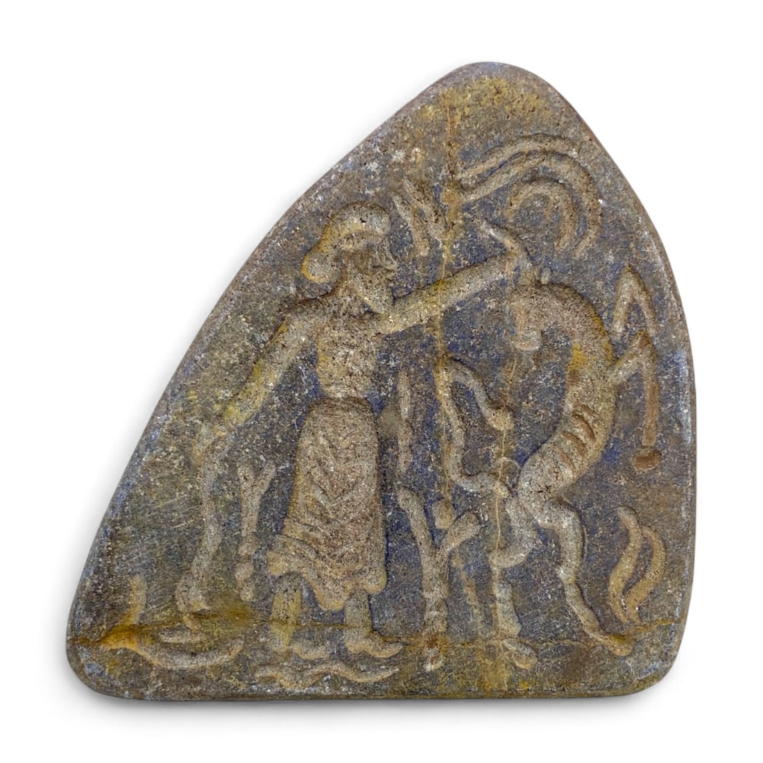 Ancient Near Eastern Heroic Combat Scene Schist Relief Plaque, c. 2nd Millennium BCE, 102g: This evocative ancient schist relief plaque, carved in a dramatic wedge form and weighing 102 grams, depicts a heroic combat scene emblematic of Near Eastern mythological or epic traditions. Measuring