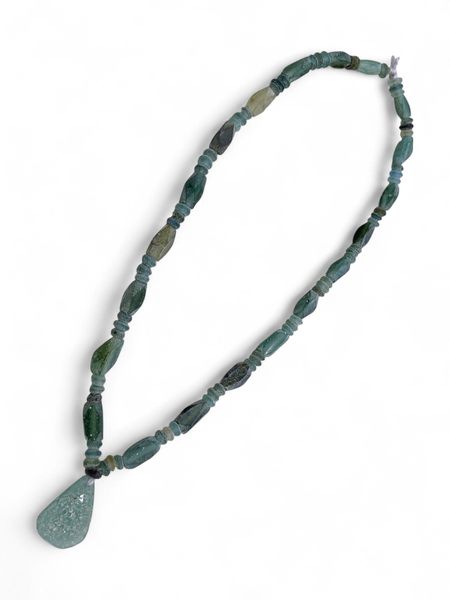 Ancient Roman Aqua Glass Bead Strand with Pendant, c. 1st-3rd Century CE, 24g: This delicate and luminous strand of ancient Roman glass beads, dating to the 1st-3rd century CE, embodies the refined elegance and global influence of Roman glassmaking. Crafted in subtle shades of a