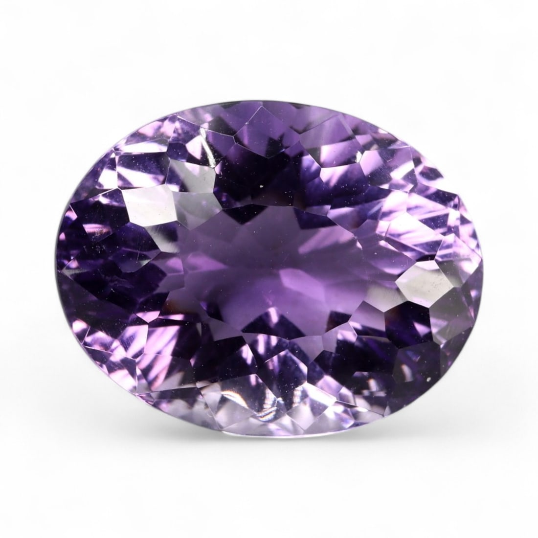 14.75 Carats Lavender Violet Amethyst Oval - Natural Brazilian Stone: This amethyst commands attention with its refined oval cut and soft yet saturated blend of lavender and deep violet hues. The gem displays a silky brilliance, with radiant-style faceting that enhances