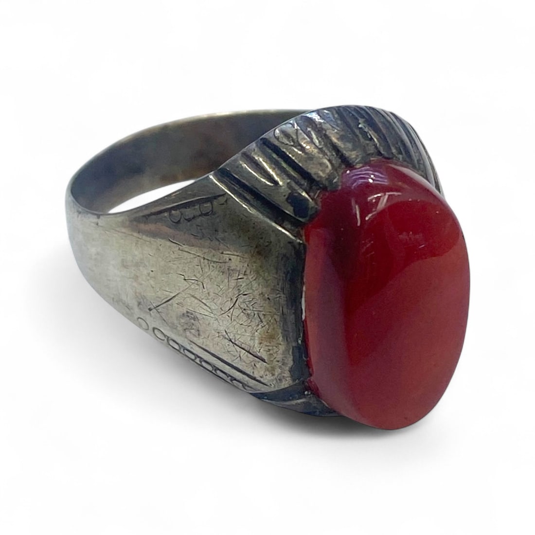 Antique Mid-20th Century Silver Ring with Red Carnelian and Radiating Bezel Design, 8g: This antique silver ring showcases a rich red oval carnelian cabochon, set within a raised bezel framed by radiating grooves that extend into the shoulders. The design draws focus to the gemstone whil