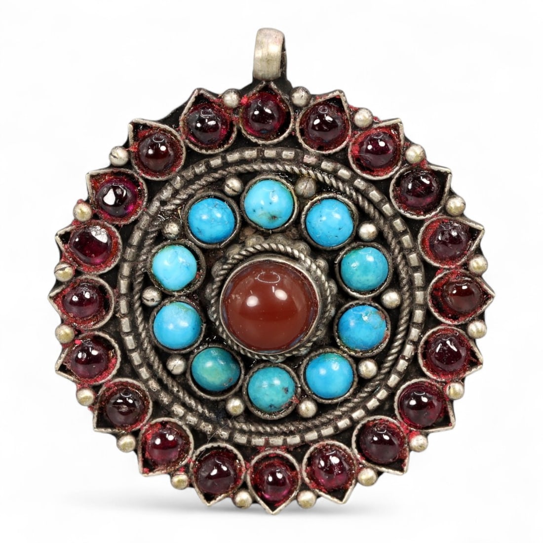 Antique Himalayan Mandala-Form Silver Pendant with Turquoise and Garnet Inlays, 20th Century, 11g: This radiant Himalayan pendant, crafted in the 20th century, draws its inspiration from sacred mandala forms central to Tibetan and Nepalese spiritual traditions. Arranged in precise concentric circle