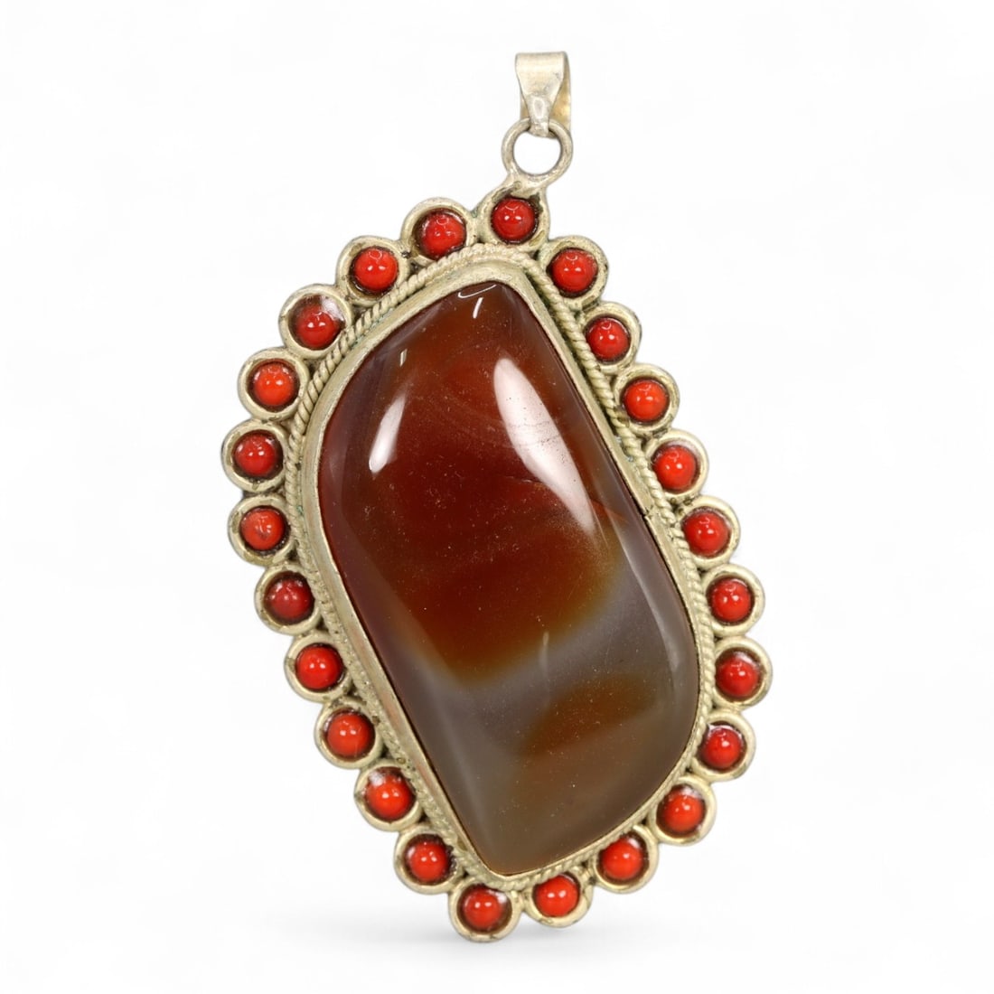 Antique Himalayan Carnelian and Coral Bezel Silver Pendant, 20th Century, 22g: This bold and refined Himalayan pendant showcases a commanding presence through its central polished carnelian cabochon, set in a traditional silver bezel and framed by a scalloped halo of vivid coral