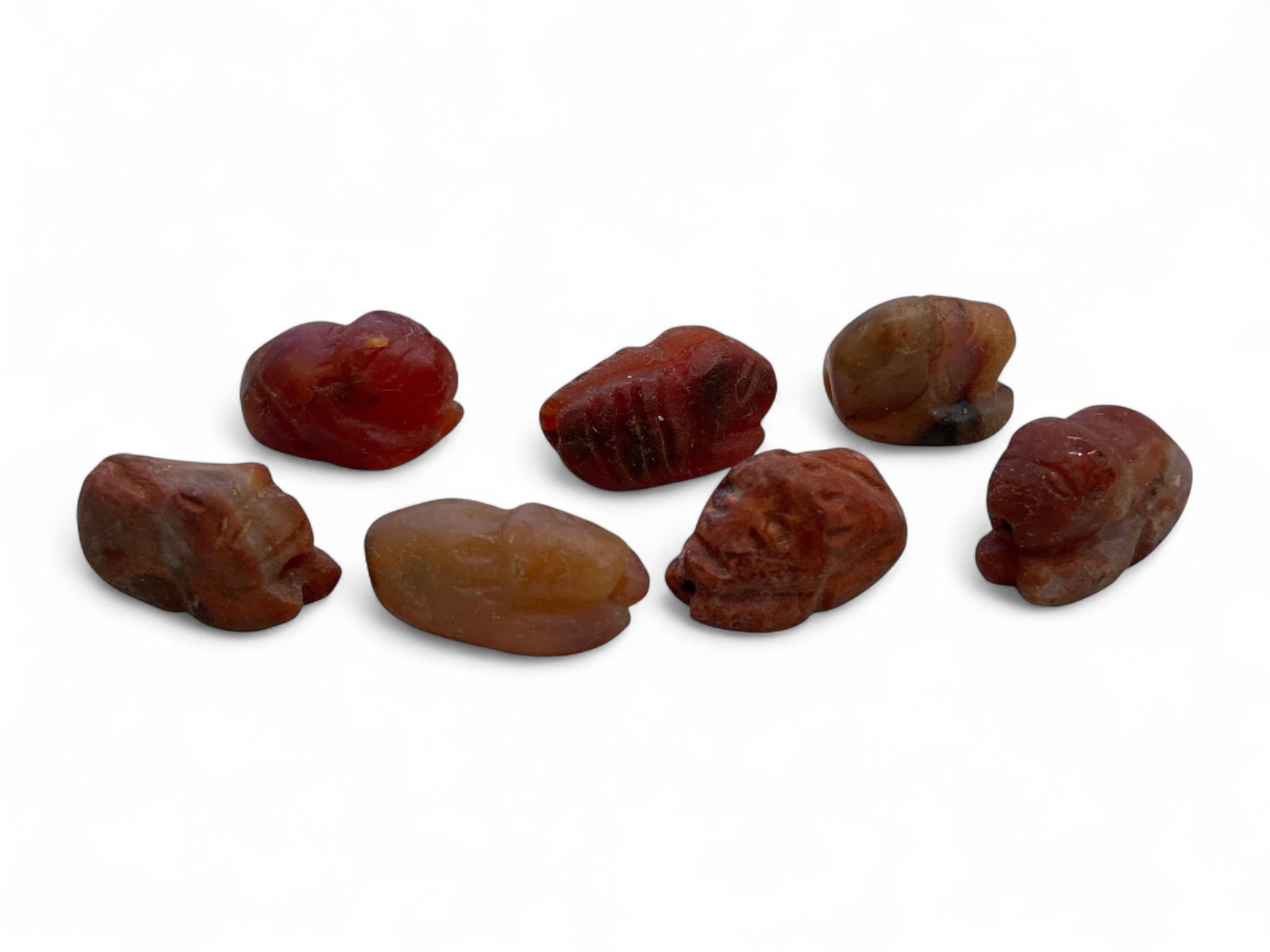 Ancient Coptic Egyptian Zoomorphic Carnelian Amulet Bead Group, c. 5th-7th Century CE, 24g: This captivating group of seven ancient Coptic Egyptian amulet beads, each hand-carved from richly hued carnelian, reflects a unique blend of spiritual artistry and devotional craftsmanship from the e