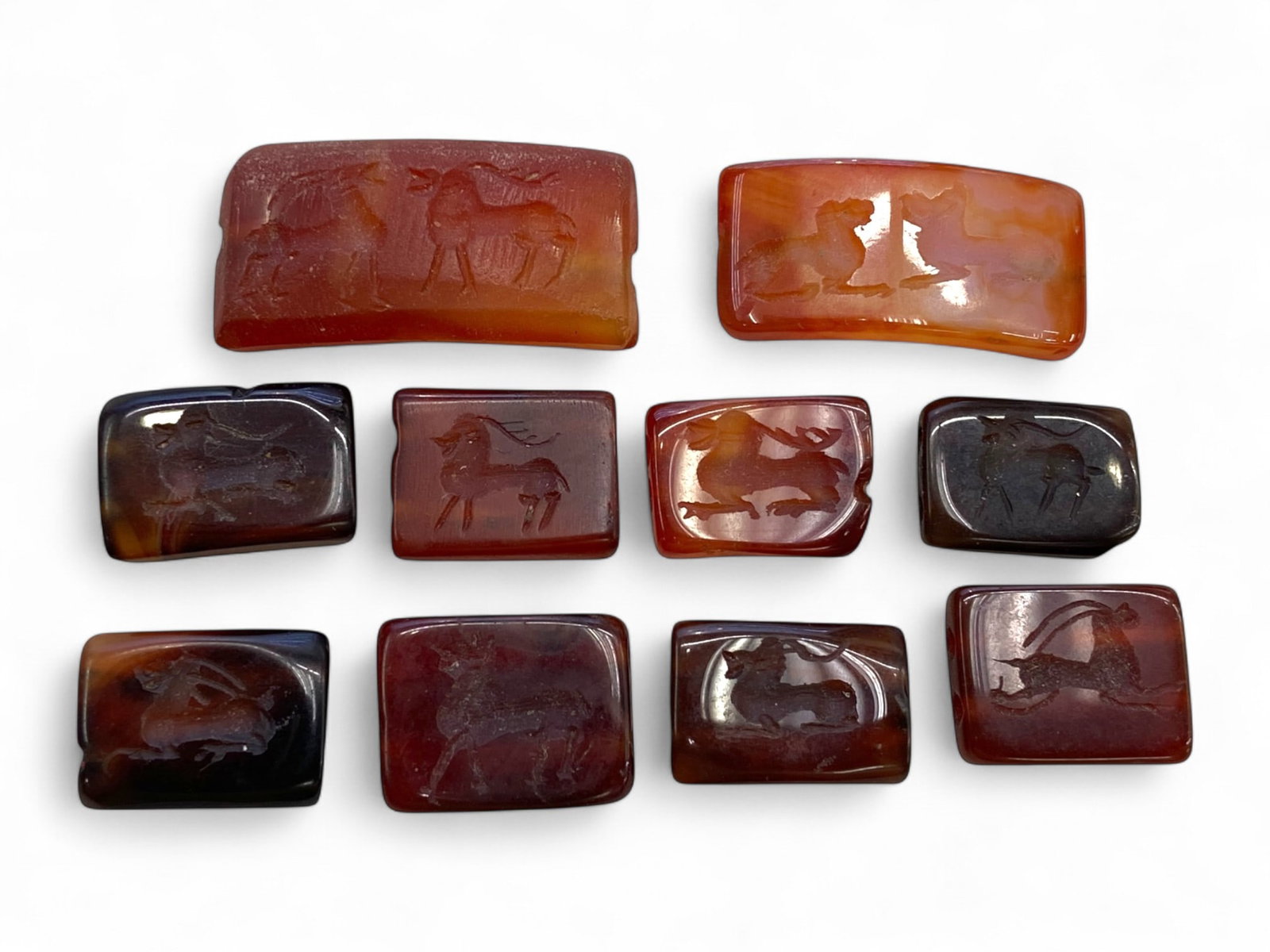 Ancient Greco-Persian and Near Eastern Carnelian Intaglio Collection, c. 5th BCE-3rd CE (33g): This stunning ensemble of ten rectangular and oval intaglios, meticulously carved in rich shades of red and amber carnelian, presents an extraordinary display of ancient artistic refinement and cultur
