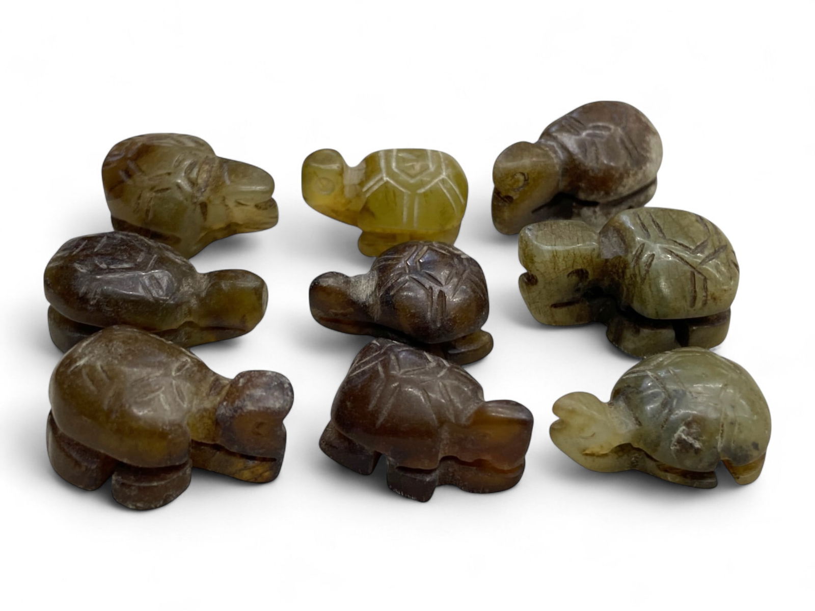 Antique Chinese Jade Miniature Tortoise Amulets Symbolizing Longevity, Early 20th Century, 31g: This charming group of nine antique jade tortoises captures the symbolic reverence for longevity and spiritual grounding within Chinese tradition. Carved from varied hues of green, brown, and honey-to