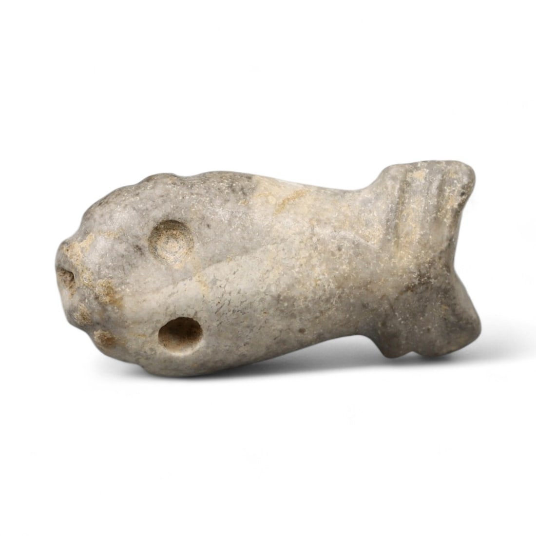 Ancient Egyptian Symbolic Fish Amulet Bead in Stone, c. 2nd Millennium BCE, 1.4g: Carved from a smooth, gray-toned stone, this petite fish-shaped amulet bead reflects the elegant symbolism of ancient Egyptian spiritual life. Measuring 2 cm in length and weighing just 1.4 grams, it 