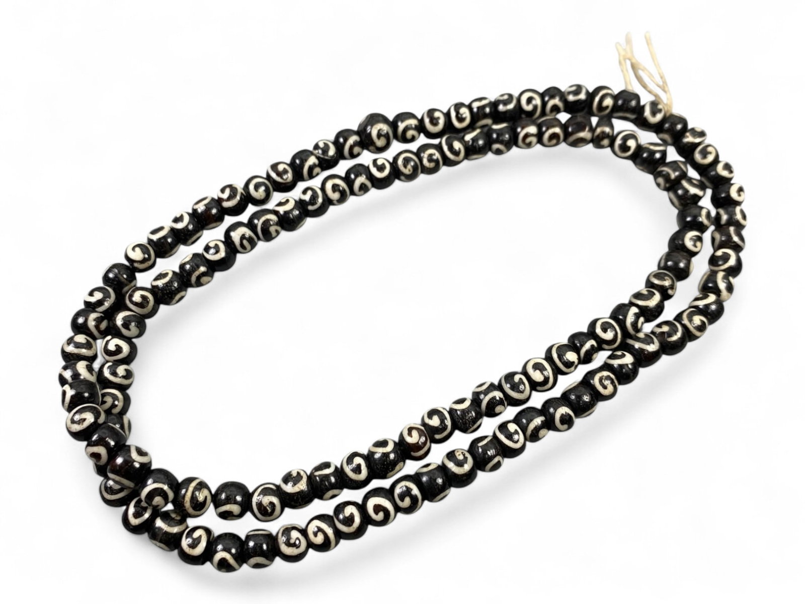 Vintage Tibetan Spiral Motif Bone Beads Strand, Unstrung, c. Mid-20th Century CE, 32g: This vintage strand of Tibetan bone beads showcases a mesmerizing spiral motif, symbolizing continuity, spiritual evolution, and the cyclical nature of life. Each bead has been meticulously hand-carve