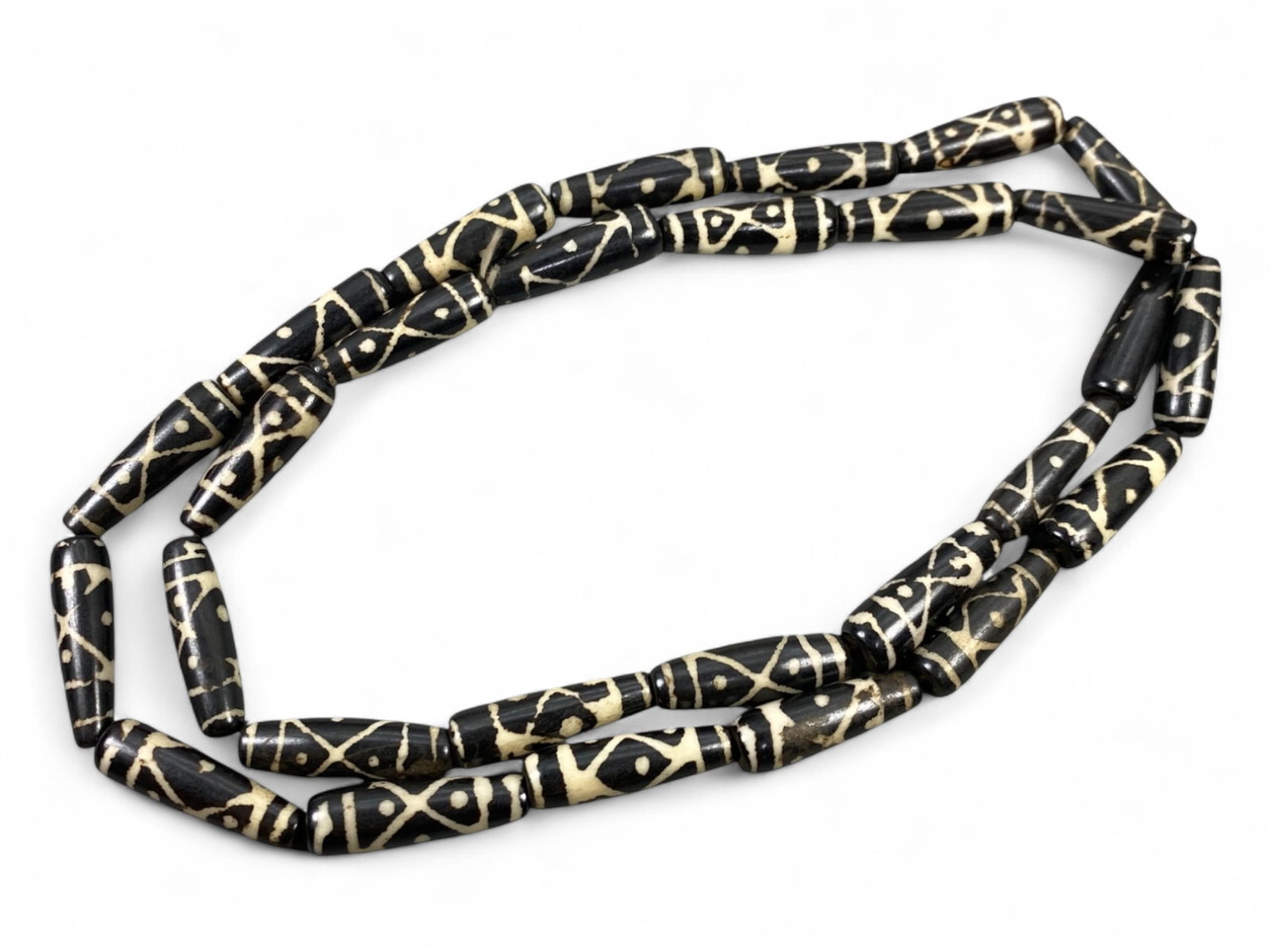 Vintage Tibetan Geometric Motif Black Yak Bone Beads Strand, Unstrung, c. 20th Century, 46g: This visually bold strand of vintage Tibetan yak bone beads features a striking black finish with intricate ivory-toned geometric engravings. The beadwork embodies a traditional Himalayan design ethos