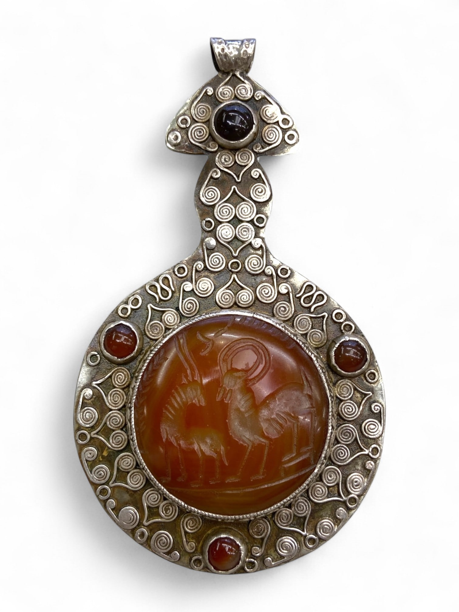Antique Persianate Ibex Pair Intaglio Spiral Silver Alloy Pendant, c. 19th-Early 20th Century CE,: A beautifully composed pendant blending regal symbolism with artistic revival, this Persianate piece showcases a carved carnelian intaglio of two ibexes - ancient symbols of fertility, strength, and s