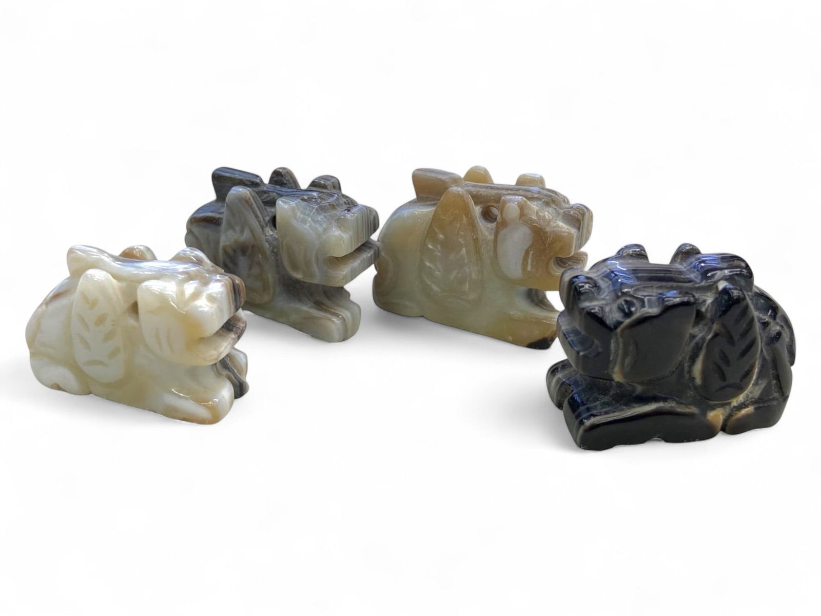 Antique Chinese Guardian Beast Jade Effigies Set, c. Late 19th-Early 20th Century CE, 49g: This captivating set of four Chinese jade effigies represents guardian beasts intricately carved in varying tones of nephrite jade, ranging from creamy pale green to deep smoky black. Dating to the la