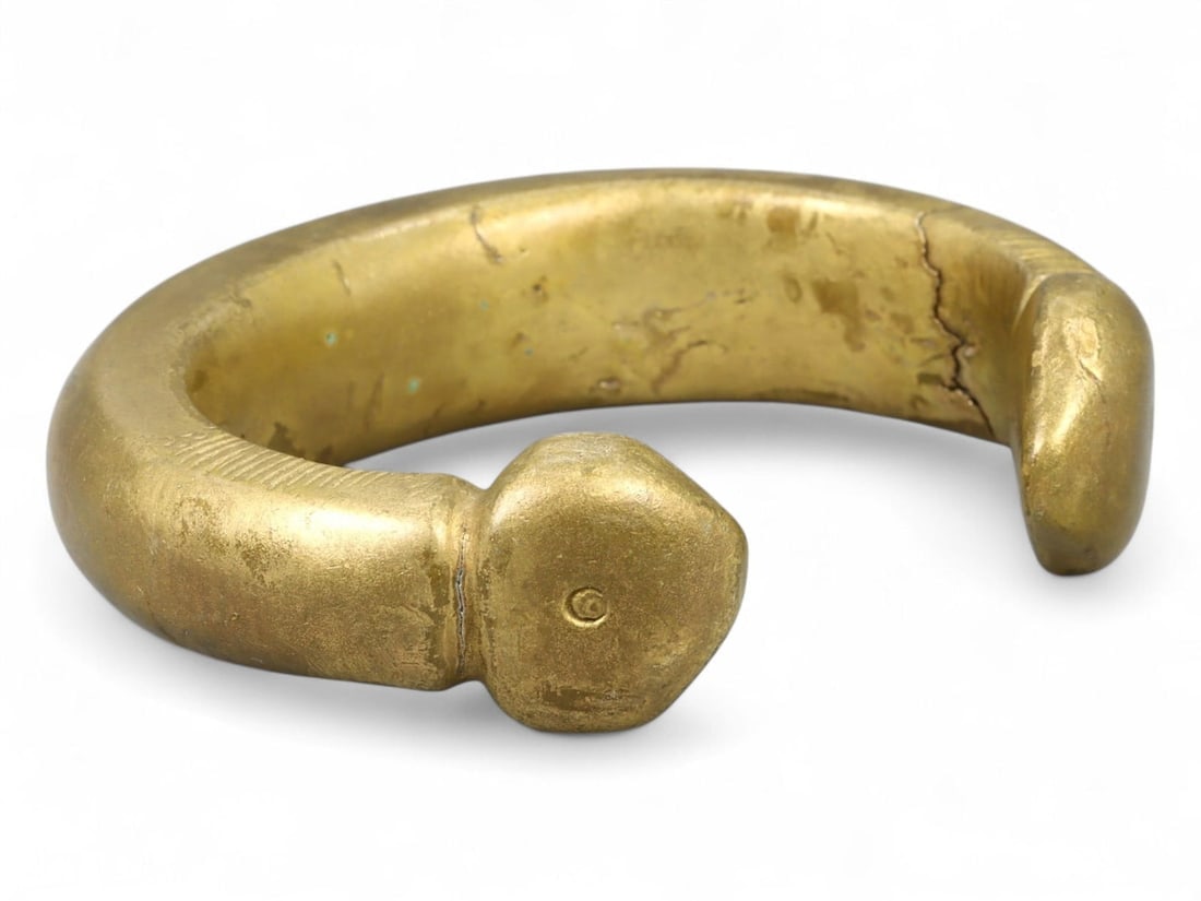 Antique West African Crescent-End Brass Manilla Bracelet, c. 17th-19th Century CE, 198g: This substantial brass manilla bracelet, weighing 198 grams (6.98 oz) and measuring 7.5 cm (2.95 inches) in diameter, is a remarkable example of West African currency adornment from the Post-Medieval 