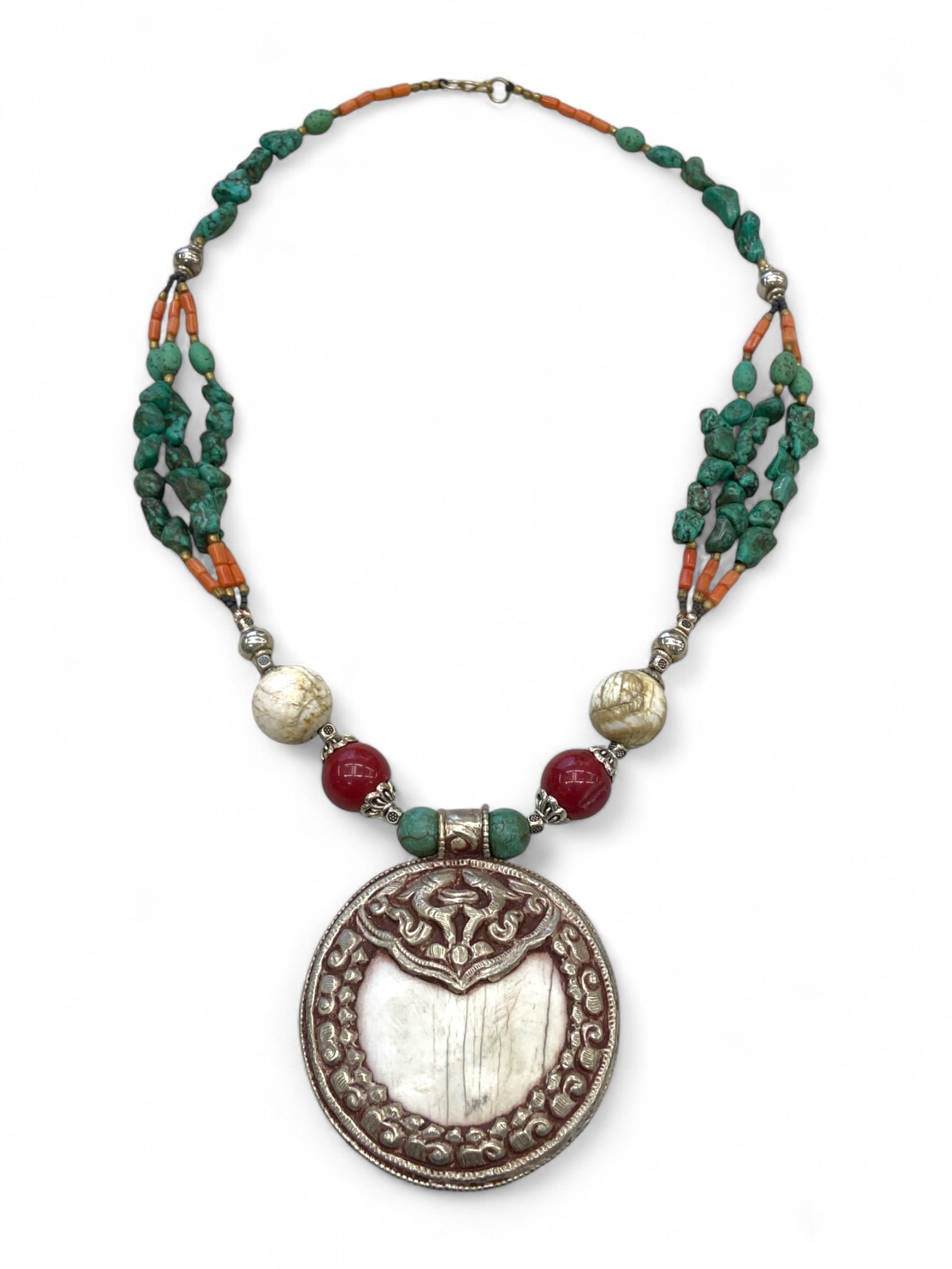 Tibetan Conch Shell Lotus Pendant Necklace, Coral-Turquoise Strand Detail - 123g: This symbolic Tibetan necklace centers on an ornate pendant crafted from polished conch shell, framed in repousse silver-toned metalwork and surrounded by floral scrolls and lotus-like forms. At the t