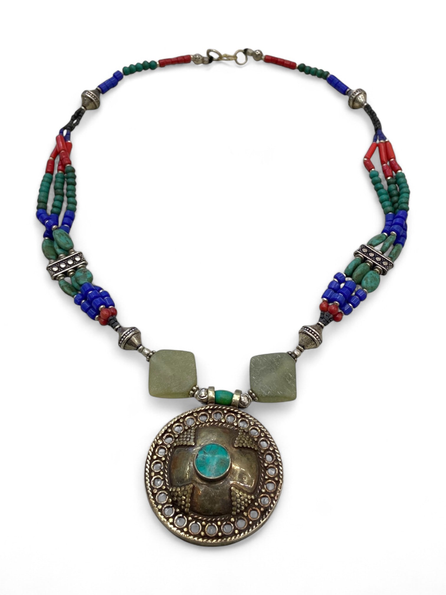 Kazakh Tribal Round Pendant Necklace with Jade, Lapis, and Turquoise, Central Asia, 60g: Rooted in the bold visual traditions of the Kazakh steppe, this striking necklace centers around a large domed pendant with a raised cross-like motif surrounding a turquoise cabochon. The circular fra