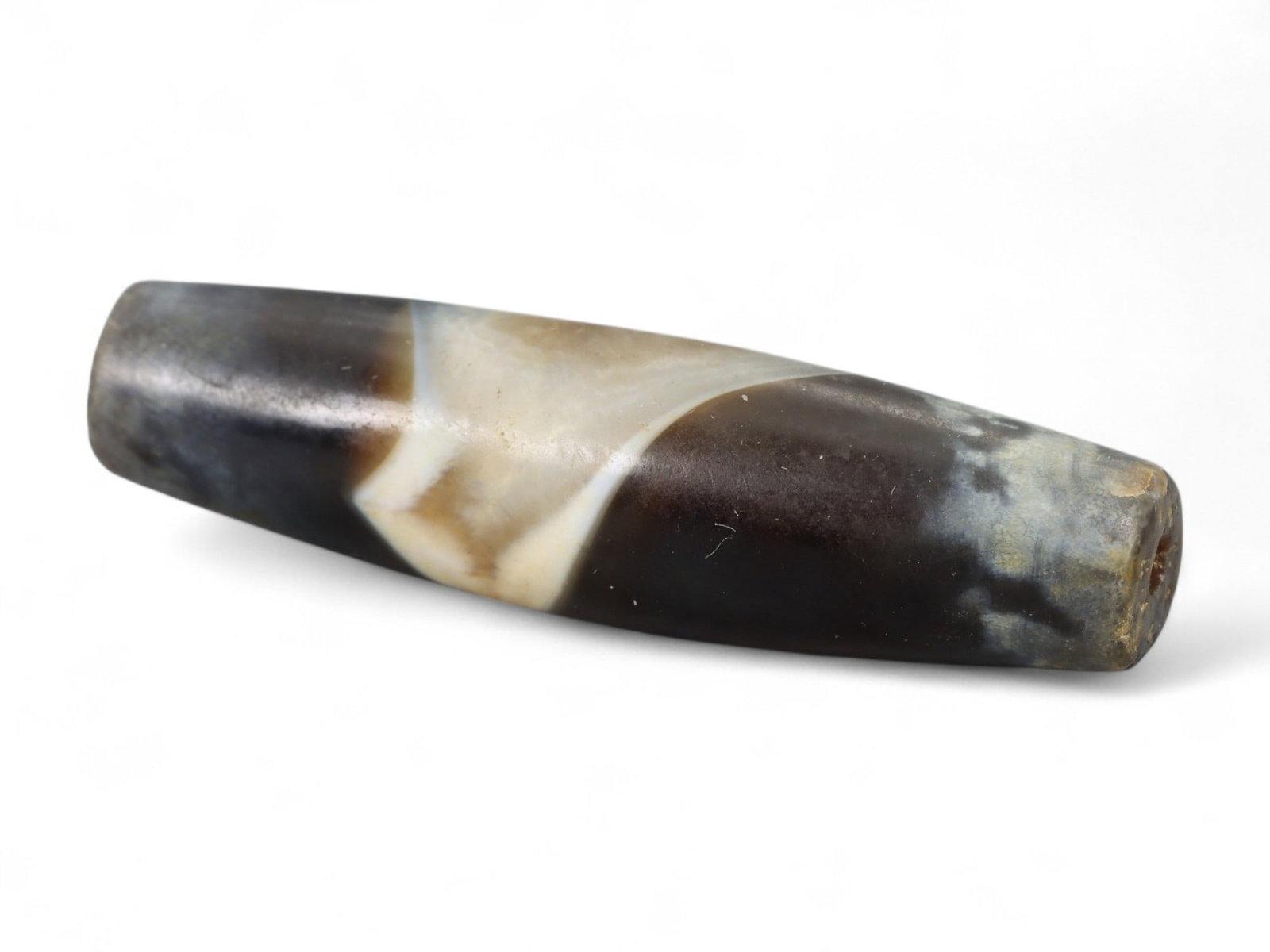 Ancient Indus Valley Long Banded Agate Barrel Bead, c. 3rd Millennium BCE, 2.7cm, 2.2g: This elongated barrel bead of banded agate, originates from the Indus Valley Civilization (c. 3300-1300 BCE). The bead exhibits finely tapered ends and striking natural banding, with deep brown, cream
