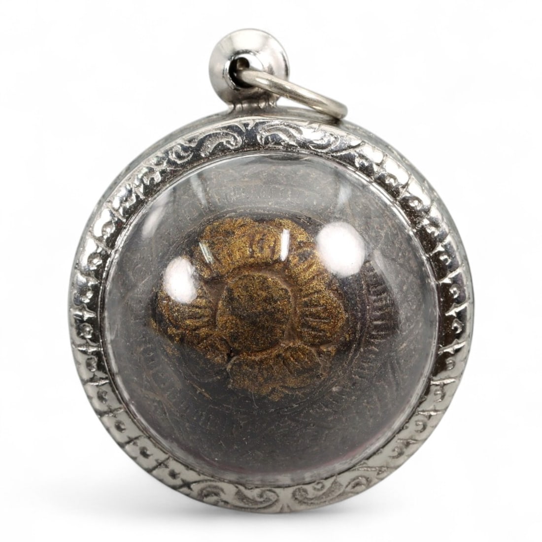 Vintage Thai Protective Amulet in Silvered Case, c. Mid-20th Century, 4.2x3.5cm, 29.4g: This striking Thai Buddhist amulet, measuring 4.2 x 3.5 cm and weighing 29.4 grams, is encased in a protective silver-colored locket with ornate engraved edging and a clear domed cover. Within lies a