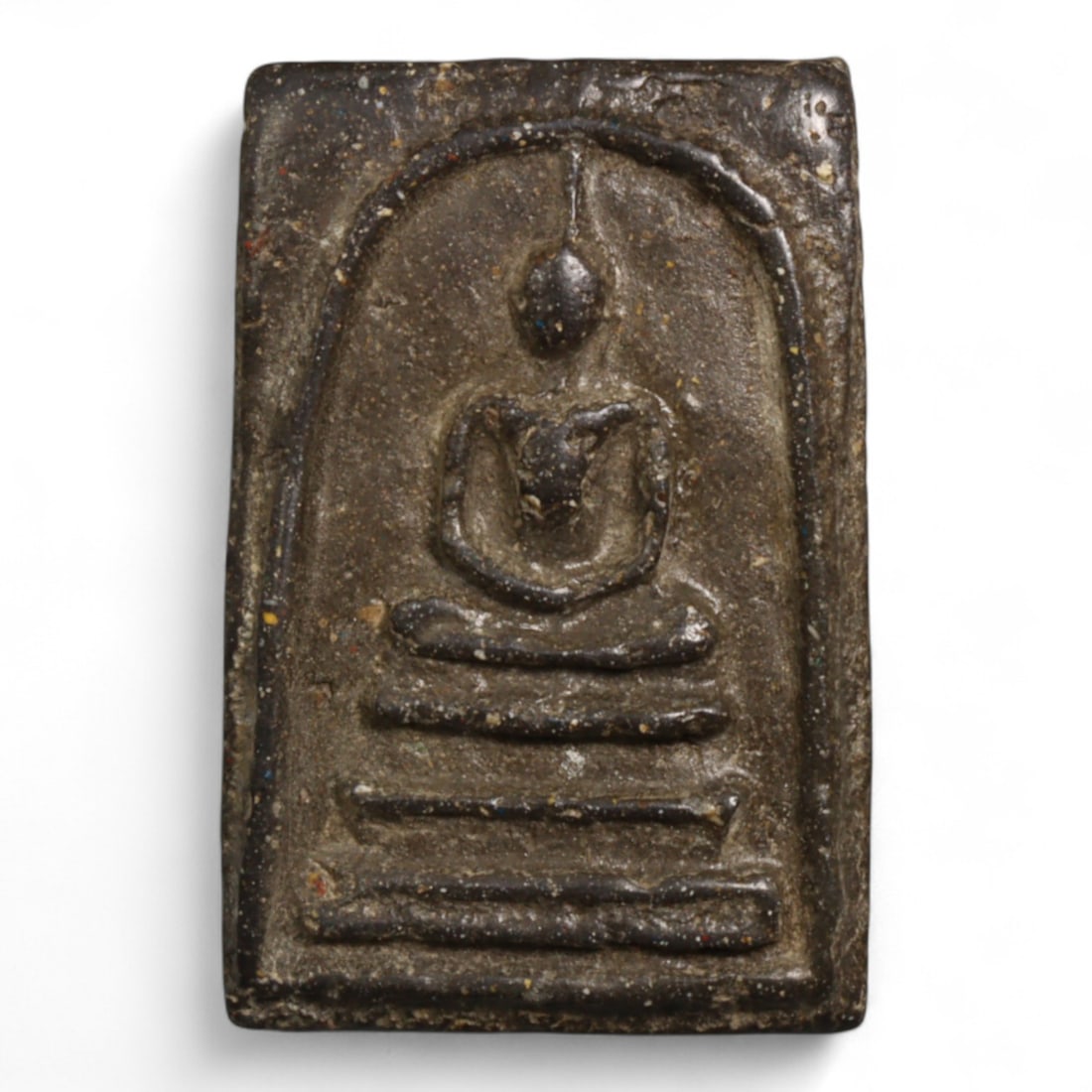 Vintage Thai Somdej Style Dark Clay Buddha Amulet, c. 20th Century - 8g: This vintage Thai Buddha amulet, rendered in the classic Somdej style, features the Buddha seated serenely in meditation on a triple-tiered base beneath an arched shrine. Cast in dark clay with a coar