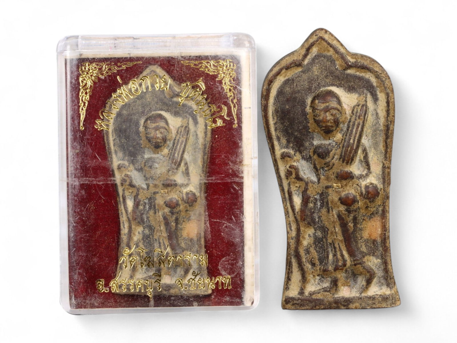 Vintage Thai Buddhist Amulet in Original Temple Box, c. Mid-20th Century: This vintage Thai Buddhist amulet, is preserved in its original temple presentation box. Crafted in sacred clay and inset with horizontal metal strips, the amulet depicts the serene figure of the Budd