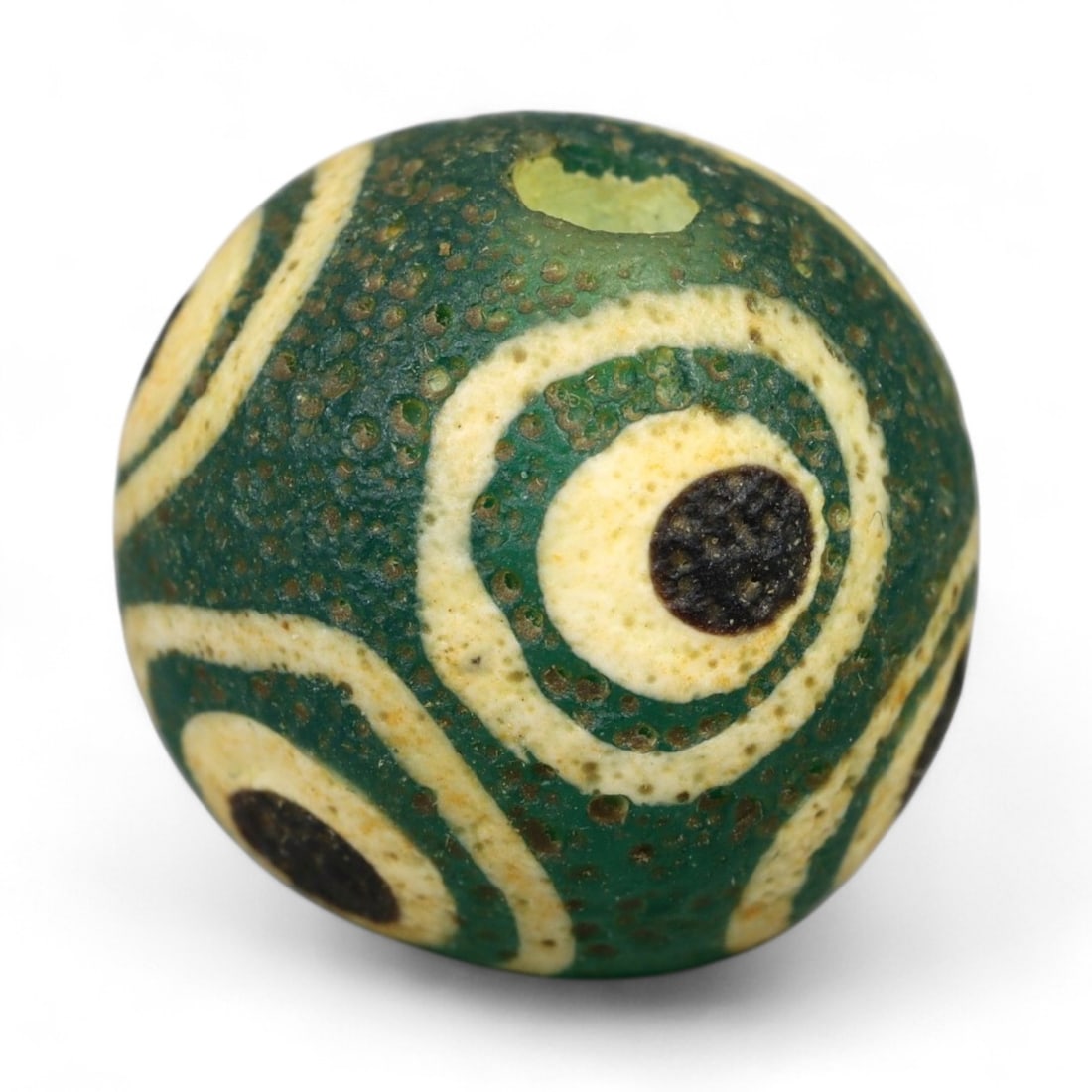 Ancient Roman Stratified Glass Eye Bead, c. 1st-3rd Century CE, 1.2cm: This finely crafted Roman glass eye bead, dating from the 1st to 3rd century CE, measures 1.2 cm in diameter. Formed through stratified layers of colored glass, it displays concentric circular "eye" m