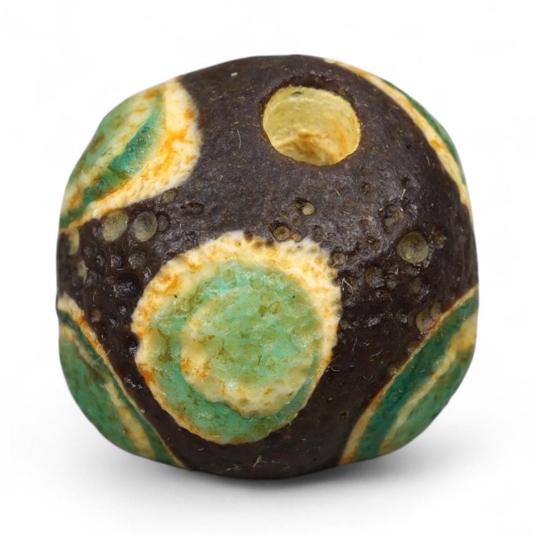 Ancient Roman Stratified Glass Eye Bead, c. 1st-3rd Century CE, 1.2cm: This finely crafted Roman glass eye bead, dating from the 1st to 3rd century CE, measures 1.2 cm in diameter. Formed through stratified layers of colored glass, it displays concentric circular "eye" m