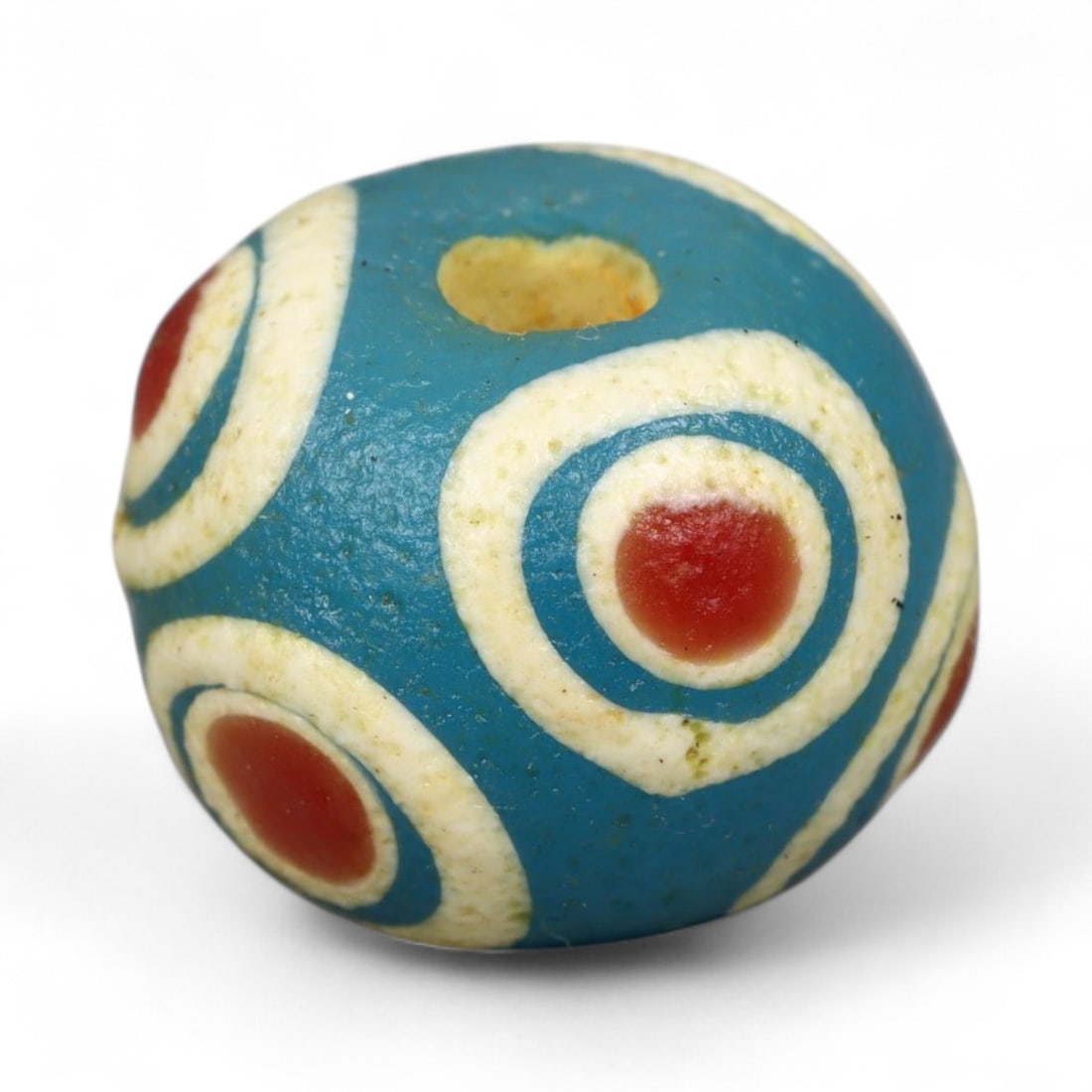 Ancient Roman Stratified Glass Eye Bead, c. 1st-3rd Century CE, 1.2cm: This finely crafted Roman glass eye bead, dating from the 1st to 3rd century CE, measures 1.2 cm in diameter. Formed through stratified layers of colored glass, it displays concentric circular "eye" m