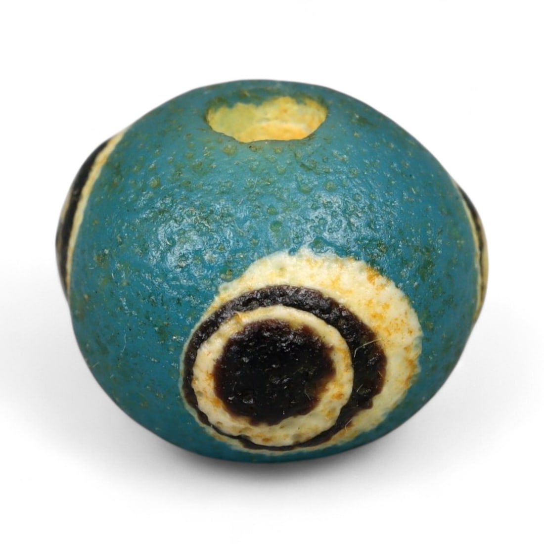 Ancient Roman Stratified Glass Eye Bead, c. 1st-3rd Century CE, 1.2cm: This finely crafted Roman glass eye bead, dating from the 1st to 3rd century CE, measures 1.2 cm in diameter. Formed through stratified layers of colored glass, it displays concentric circular "eye" m