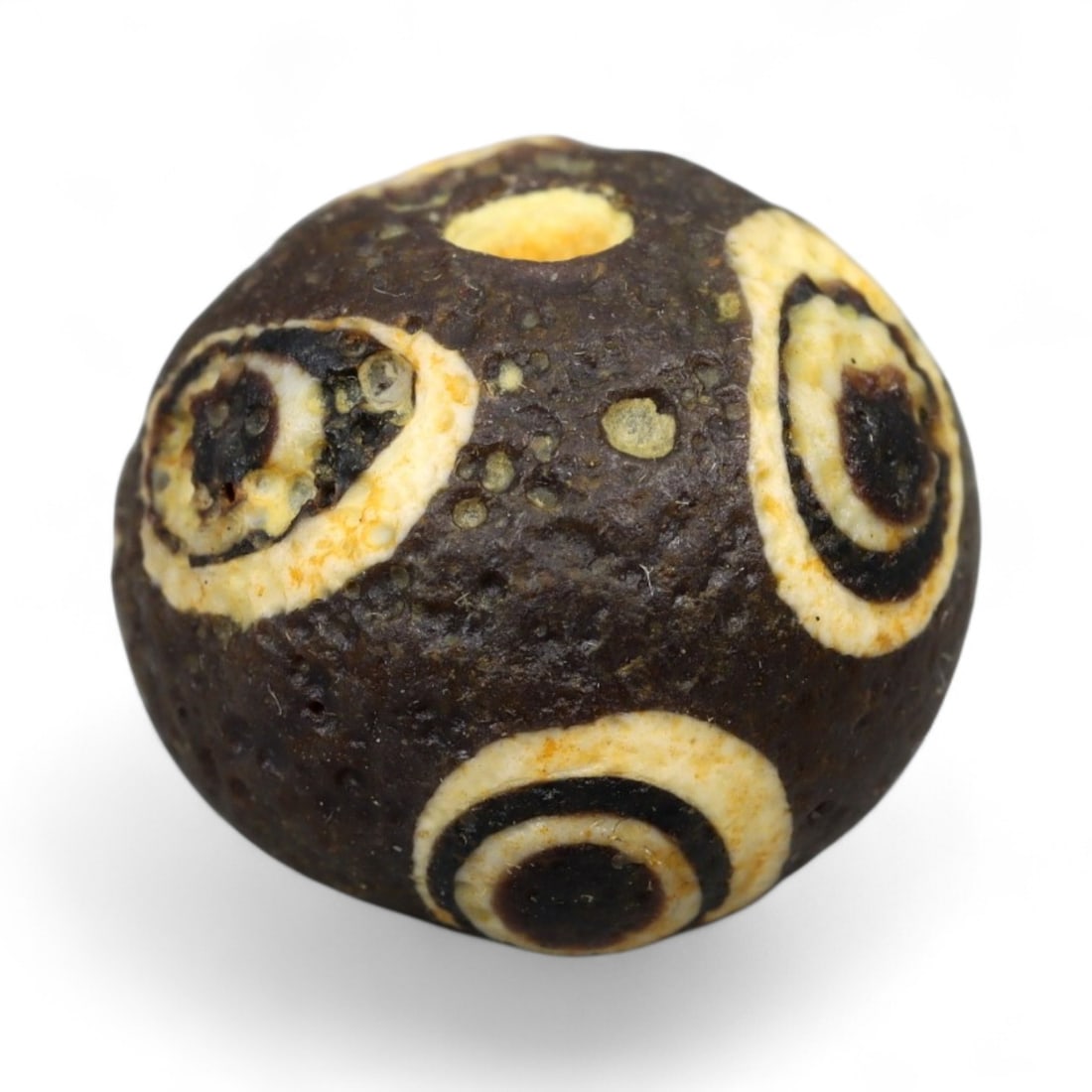 Ancient Roman Stratified Glass Eye Bead, c. 1st-3rd Century CE, 1.2cm: This finely crafted Roman glass eye bead, dating from the 1st to 3rd century CE, measures 1.2 cm in diameter. Formed through stratified layers of colored glass, it displays concentric circular "eye" m