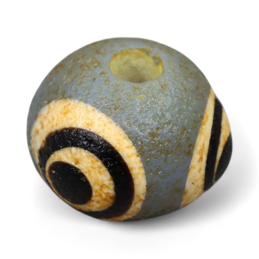 Ancient Roman Stratified Glass Eye Bead, c. 1st-3rd Century CE, 1.2cm: This finely crafted Roman glass eye bead, dating from the 1st to 3rd century CE, measures 1.2 cm in diameter. Formed through stratified layers of colored glass, it displays concentric circular "eye" m