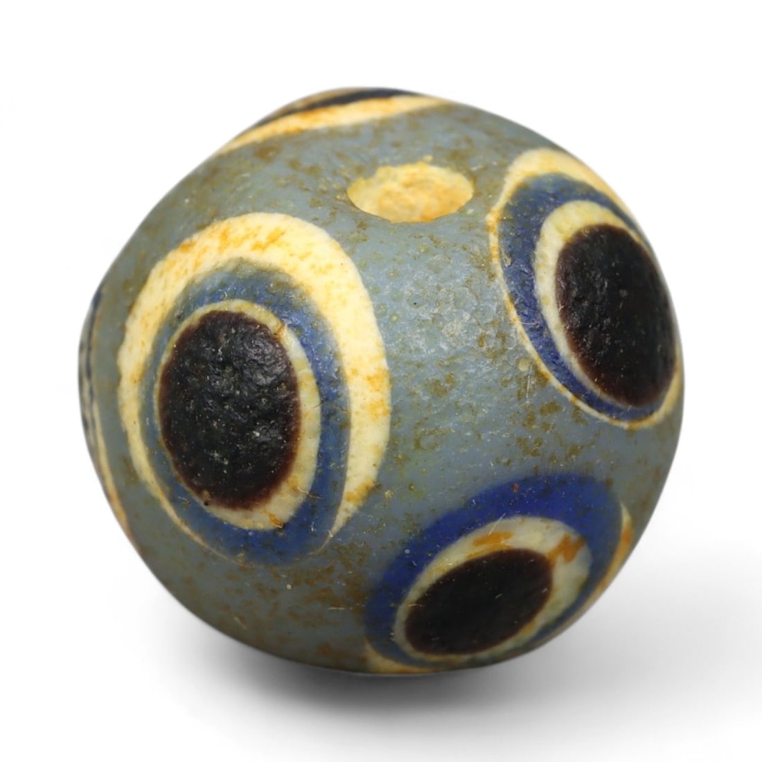 Ancient Roman Stratified Glass Eye Bead, c. 1st-3rd Century CE, 1.2cm: This finely crafted Roman glass eye bead, dating from the 1st to 3rd century CE, measures 1.2 cm in diameter. Formed through stratified layers of colored glass, it displays concentric circular "eye" m
