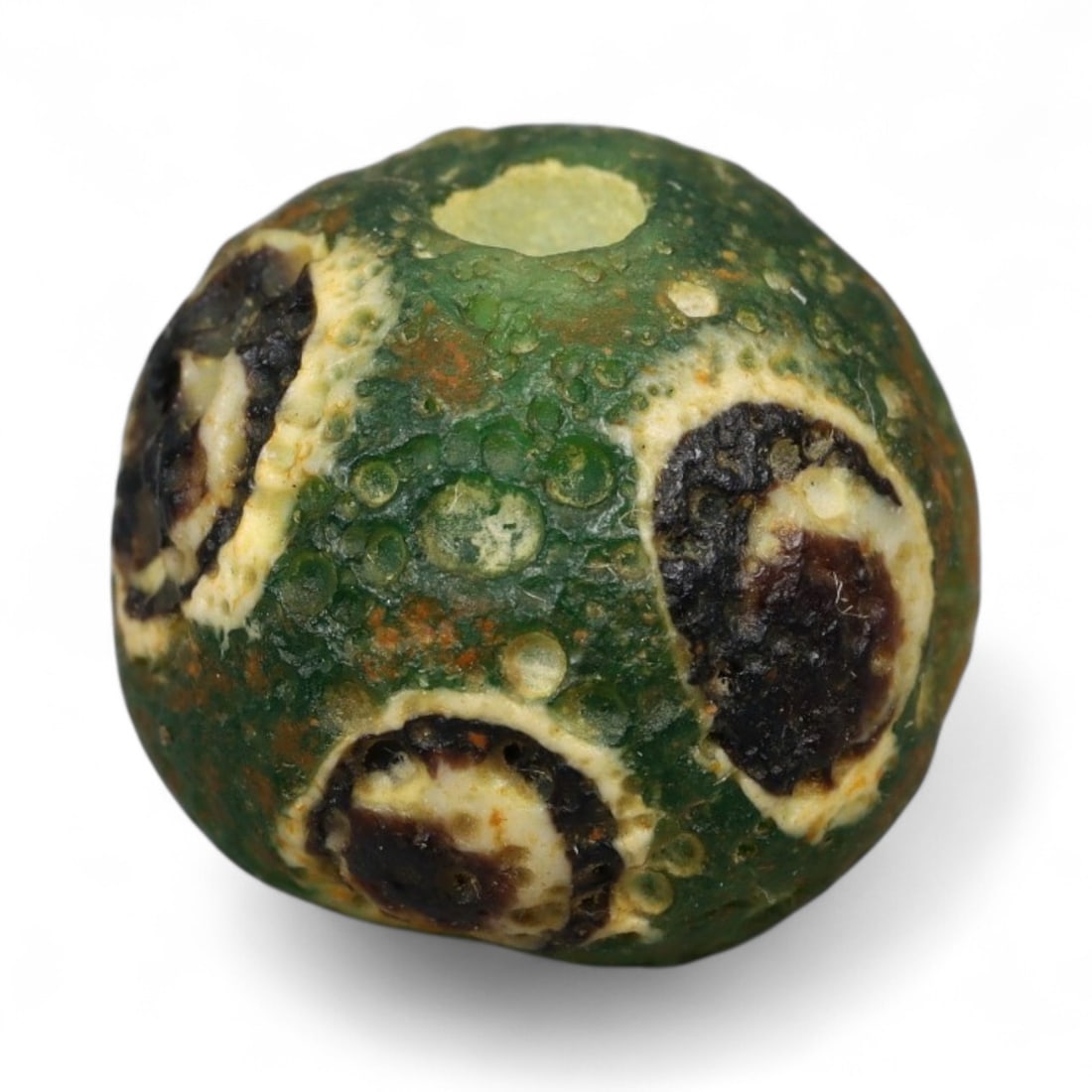 Ancient Roman Stratified Glass Eye Bead, c. 1st-3rd Century CE, 1.2cm: This finely crafted Roman glass eye bead, dating from the 1st to 3rd century CE, measures 1.2 cm in diameter. Formed through stratified layers of colored glass, it displays concentric circular "eye" m