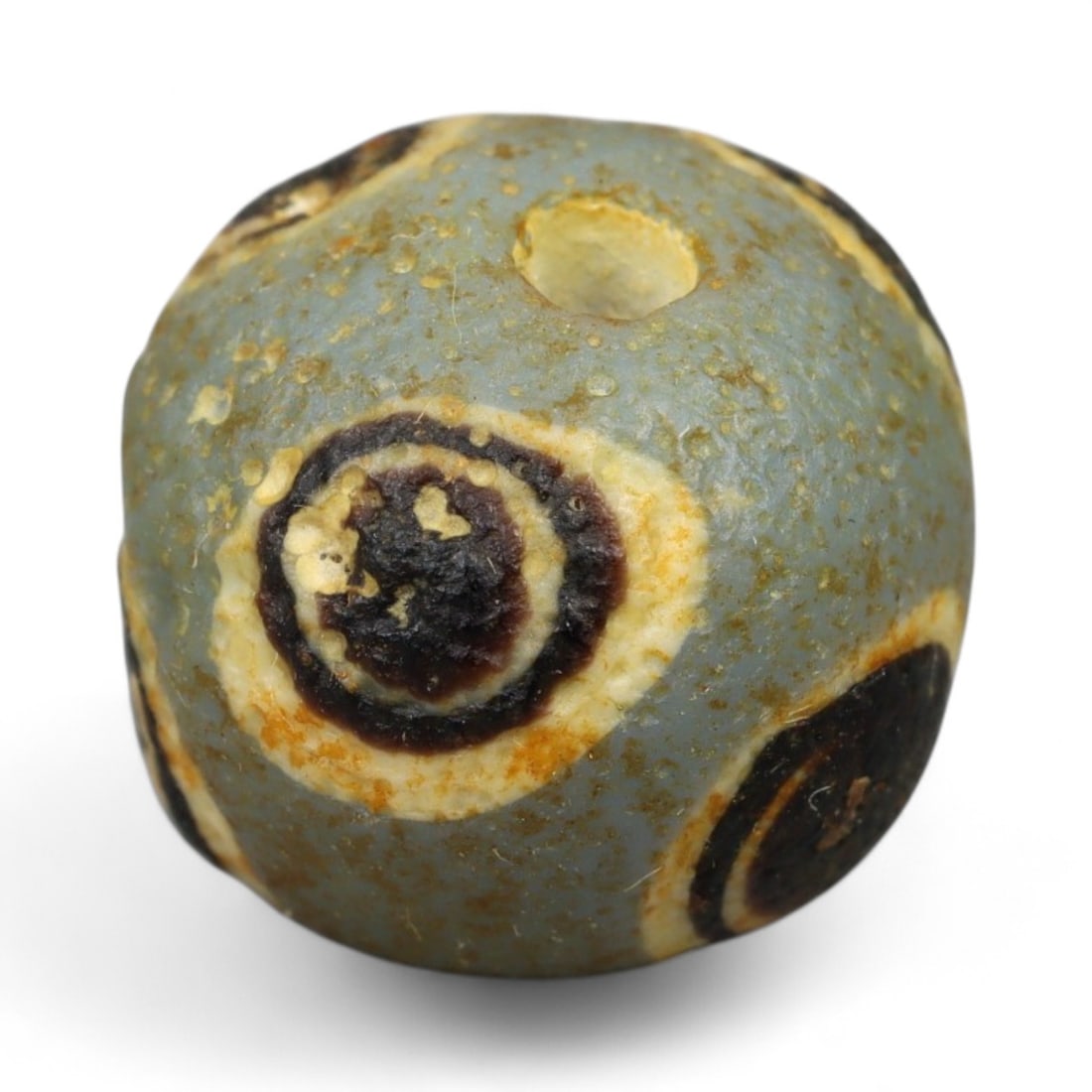Ancient Roman Stratified Glass Eye Bead, c. 1st-3rd Century CE, 1.2cm: This finely crafted Roman glass eye bead, dating from the 1st to 3rd century CE, measures 1.2 cm in diameter. Formed through stratified layers of colored glass, it displays concentric circular "eye" m