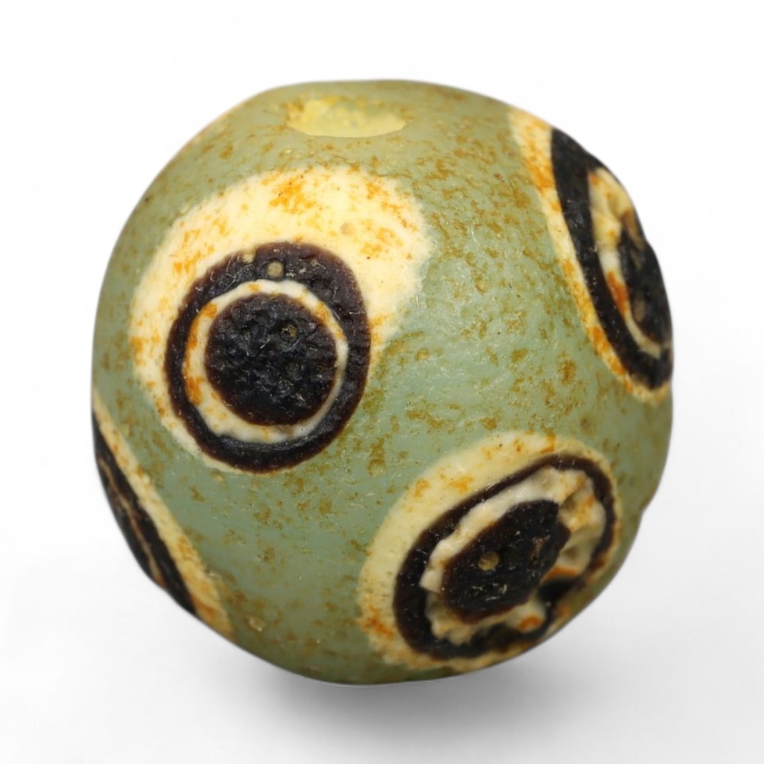 Ancient Roman Stratified Glass Eye Bead, c. 1st-3rd Century CE, 1.2cm: This finely crafted Roman glass eye bead, dating from the 1st to 3rd century CE, measures 1.2 cm in diameter. Formed through stratified layers of colored glass, it displays concentric circular "eye" m