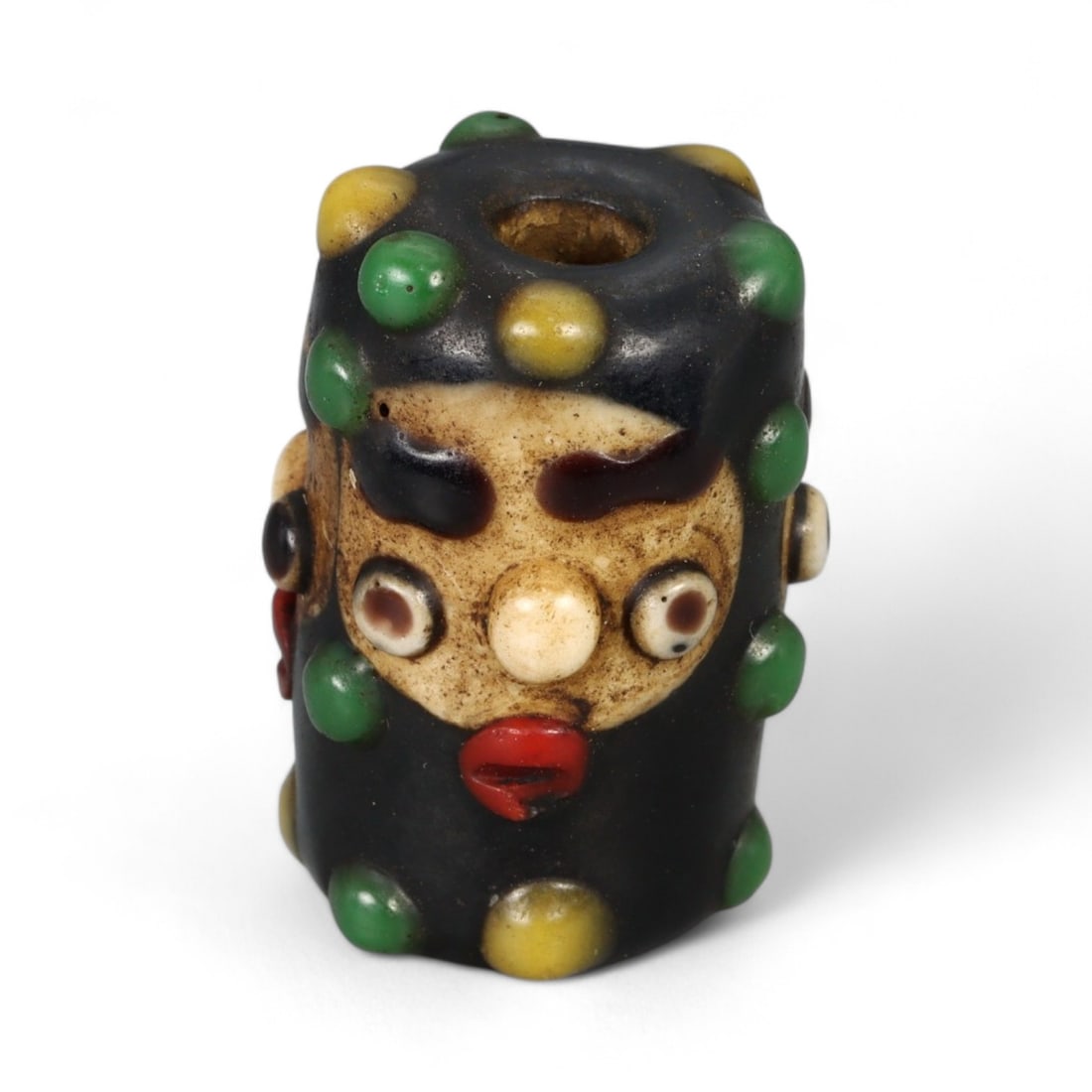 Antique Phoenician Style Multicolored Glass Face Bead, c. 19th-20th Century, 2.5cm: This vibrant antique bead is crafted in the distinctive Phoenician style, featuring a molded human face with applied multicolored details. Its bold design includes protruding eyes, a defined nose, and