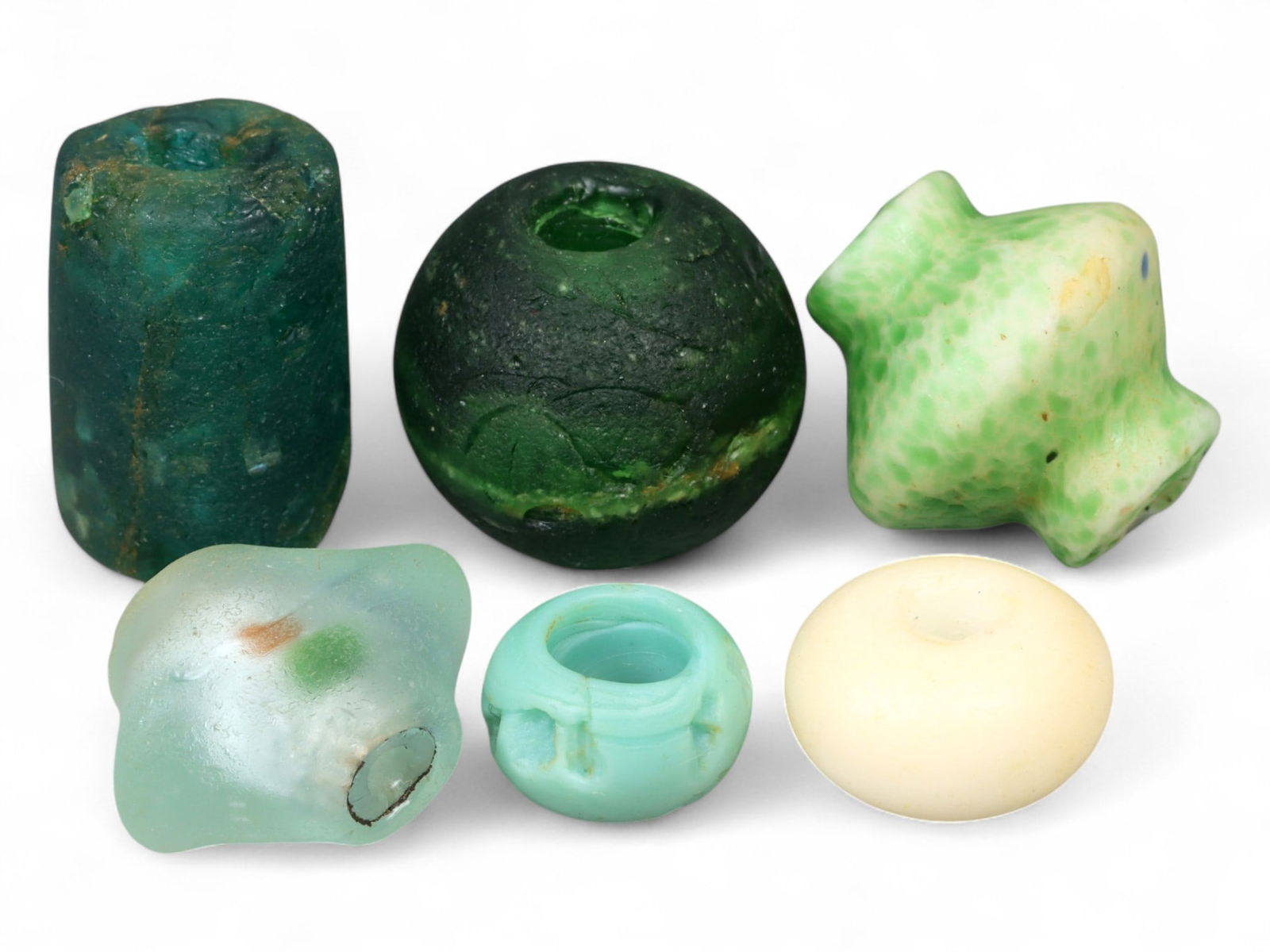 Antique Islamic Glass Bead Collection, Green and Aqua Forms, c. 18th-19th Century CE, 1.2-2cm: This collection of six antique Islamic glass beads, dating from the 18th-19th century CE, illustrates the subtle artistry of color and form within Islamic bead production. Measuring between 1.2 and 2