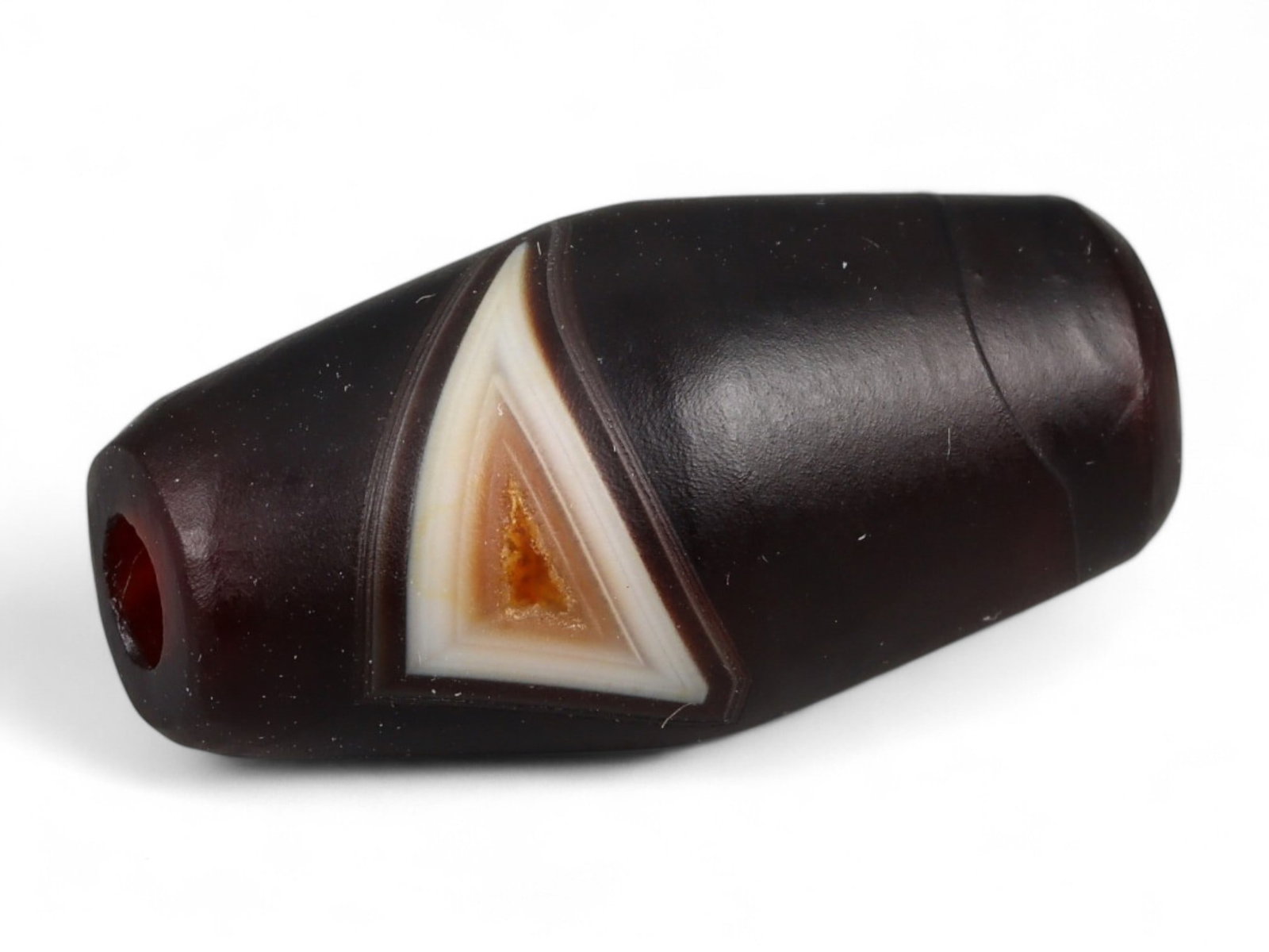 Ancient Tibetan Himalayan Banded Agate Dzi Bead, c. 9th-14th Century CE, 2.2cm: This ancient Tibetan Dzi bead, is carved from richly banded agate, its surface revealing bold layers of deep red, amber, and ivory-white. Its elongated cylindrical form, tapering at the ends, embodies
