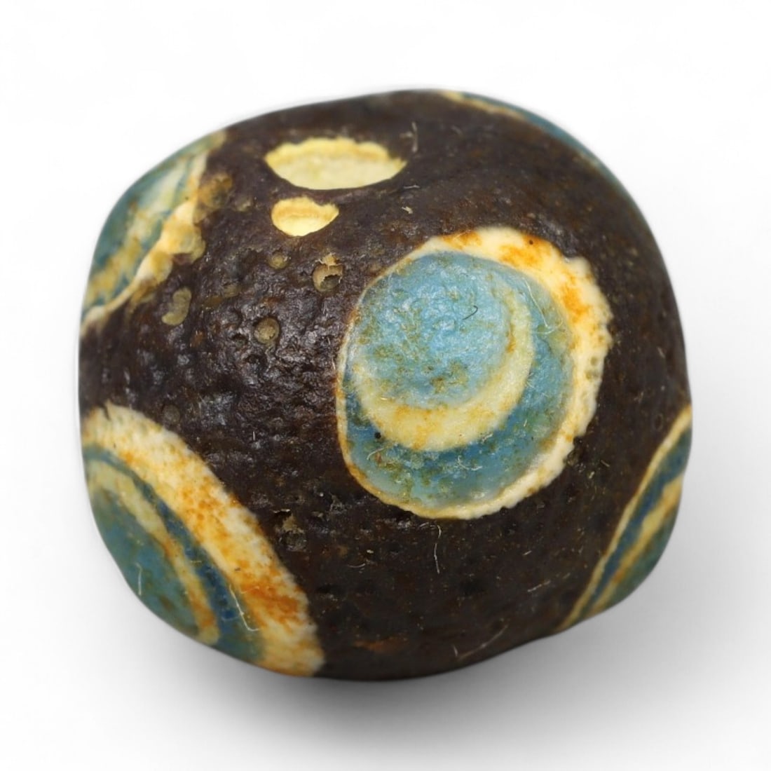 Ancient Roman Stratified Glass Eye Bead, c. 1st-3rd Century CE, 1.2cm: This finely crafted Roman glass eye bead, dating from the 1st to 3rd century CE, measures 1.2 cm in diameter. Formed through stratified layers of colored glass, it displays concentric circular "eye" m