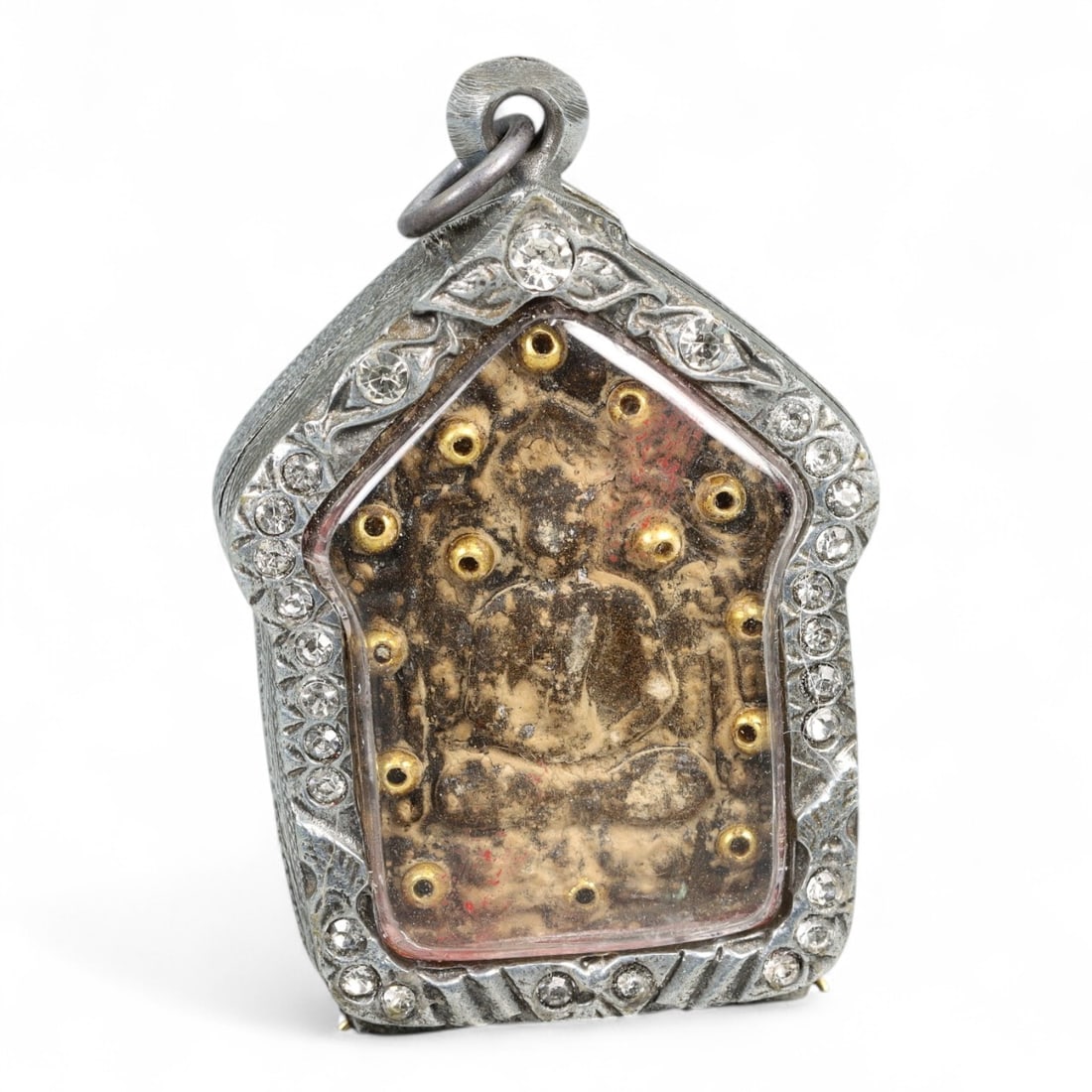 Vintage Thai Clay Buddha Amulet with Brass Inserts in Rhinestone Shrine Case, Mid-20th Century, 48g: This vintage Thai amulet presents a richly textured clay Buddha figure, weathered by time and devotion, set within a temple-shaped case adorned with floral scrollwork and sparkling rhinestones. The fi