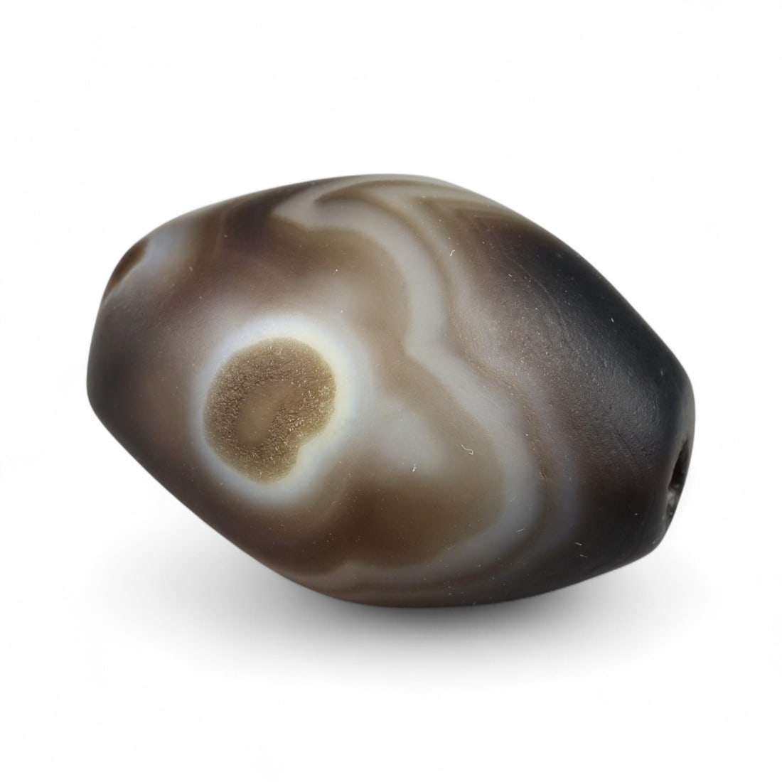 Antique Himalayan Banded Agate Amulet Bead, c. 15th-17th Century, 2.5cm: This bead, carved from banded agate with smoky brown and gray tones, dates to the Himalayan region between the 15th and 17th centuries. Its elongated oval form, shows concentric layering, a characteri
