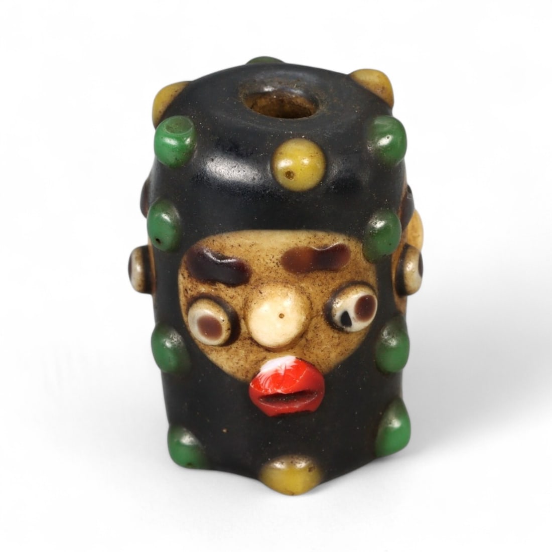 Antique Phoenician Style Multicolored Glass Face Bead, c. 19th-20th Century, 2.5cm: This vibrant antique bead is crafted in the distinctive Phoenician style, featuring a molded human face with applied multicolored details. Its bold design includes protruding eyes, a defined nose, and