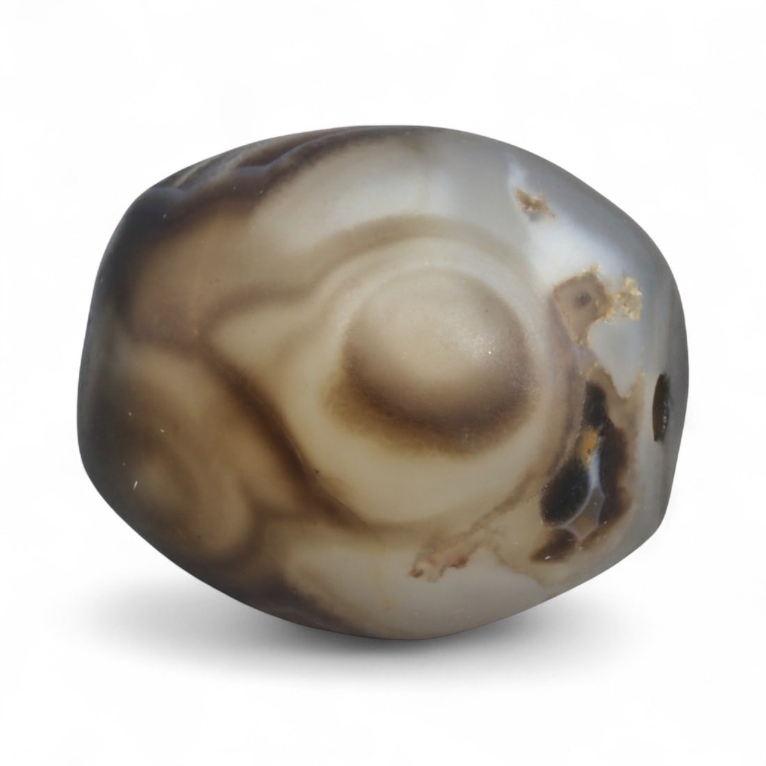 Antique Himalayan Banded Agate Amulet Bead, c. 15th-17th Century, 2.4cm: This bead, carved from banded agate with smoky brown and gray tones, dates to the Himalayan region between the 15th and 17th centuries. Its elongated oval form, shows concentric layering, a characteri