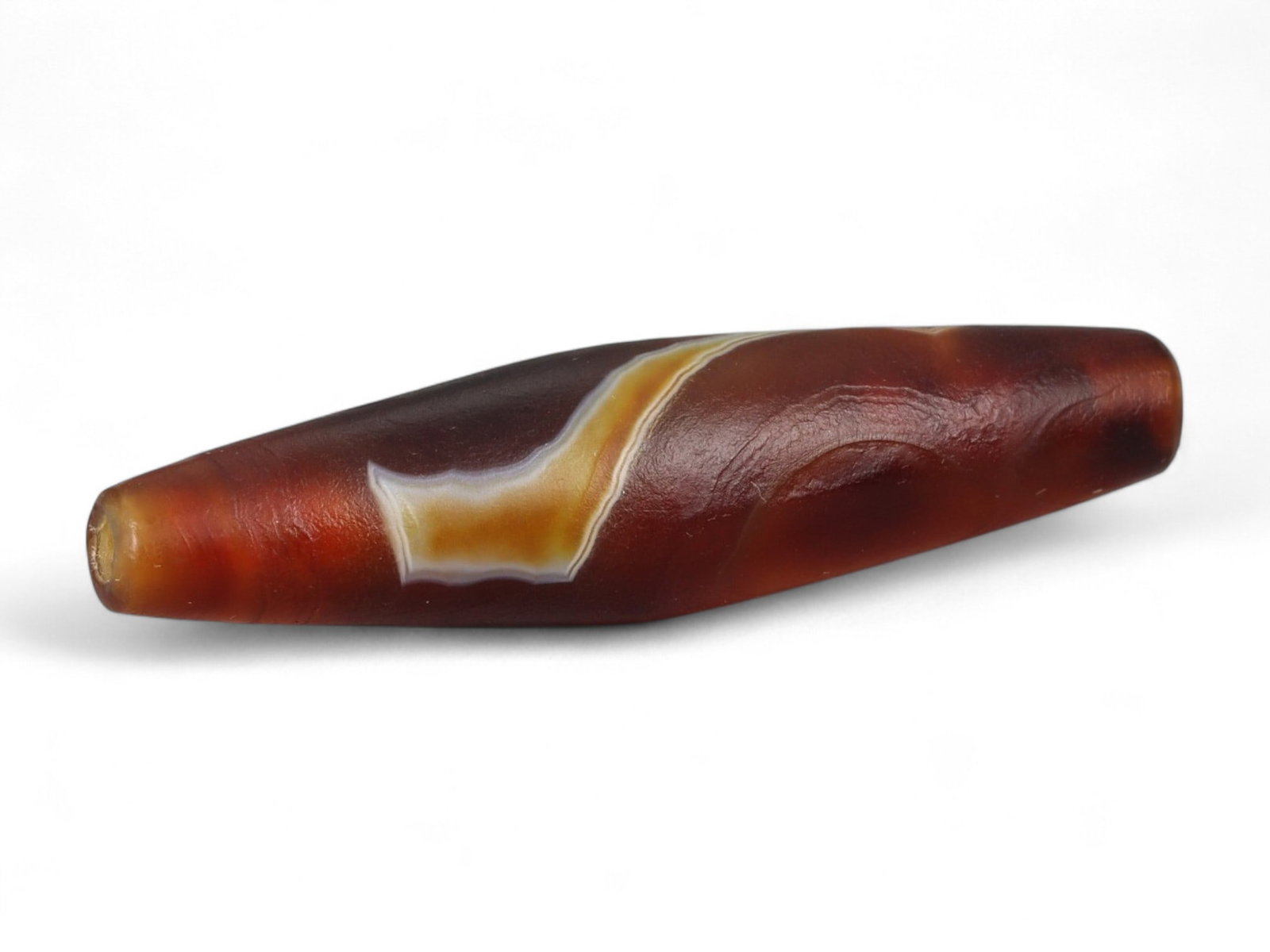 Ancient Tibetan Himalayan Banded Agate Dzi Bead, c. 9th-14th Century CE, 4cm: This ancient Tibetan Dzi bead, measuring 2.6 cm, is carved from richly banded agate, its surface revealing bold layers of deep red, amber, and ivory-white. Its elongated cylindrical form, tapering at 