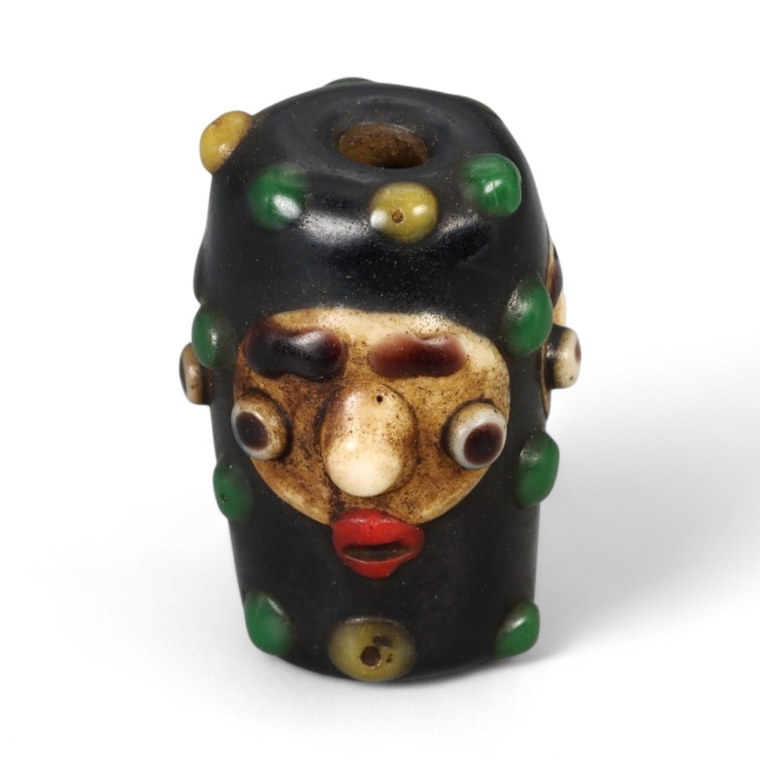Antique Phoenician Style Multicolored Glass Face Bead, c. 19th-20th Century, 2.5cm: This vibrant antique bead is crafted in the distinctive Phoenician style, featuring a molded human face with applied multicolored details. Its bold design includes protruding eyes, a defined nose, and